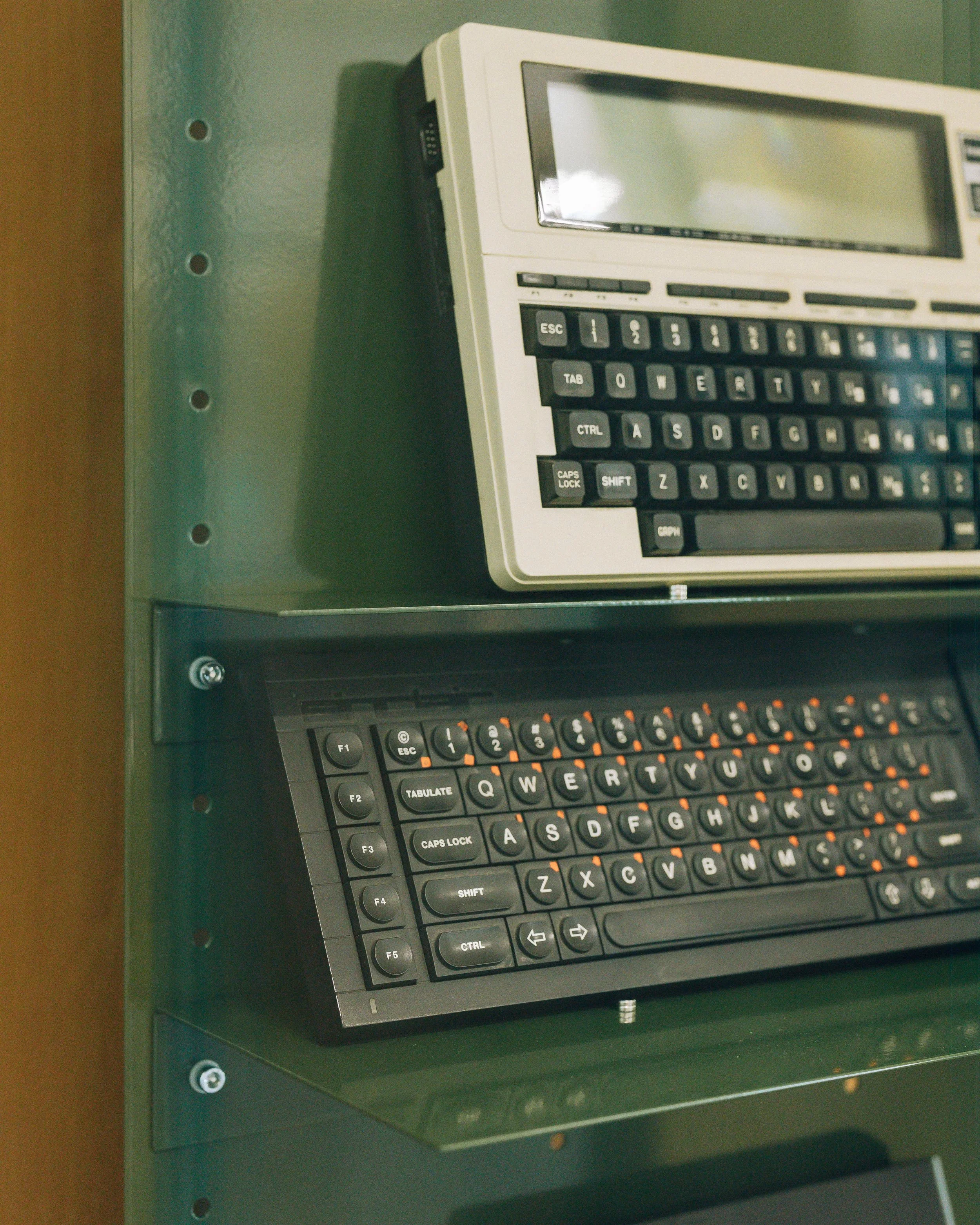 Ordinateur portable avec clavier noir et rétroéclairage orange posée sur un bureau vert.