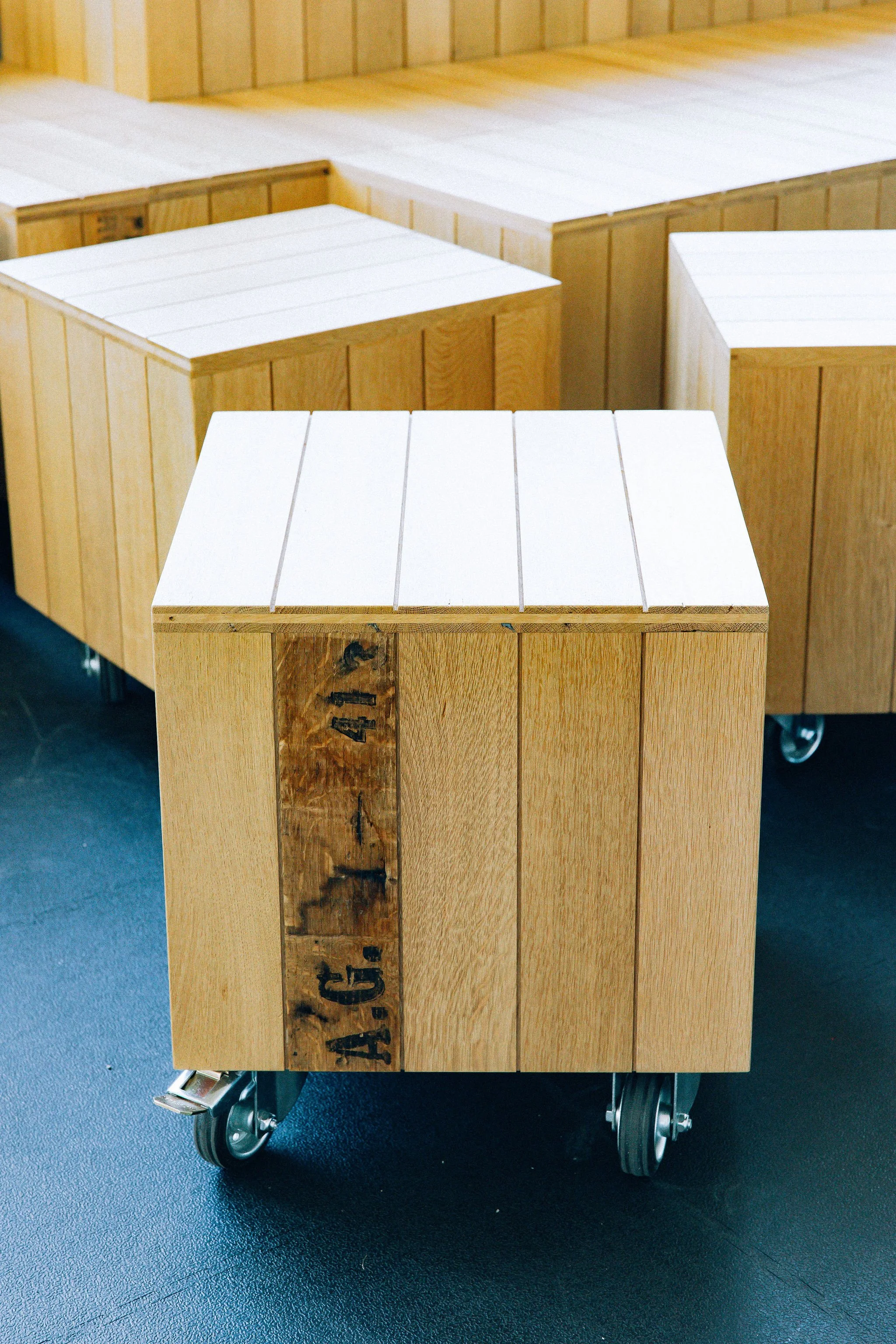 Scénographie d'exposition du projet urbanistique Praille Acacias Vernet à Genève. Détails et zoom des tabourets faits à partir de parquet massif de réemploi, situés sur un sol en caoutchouc noir.