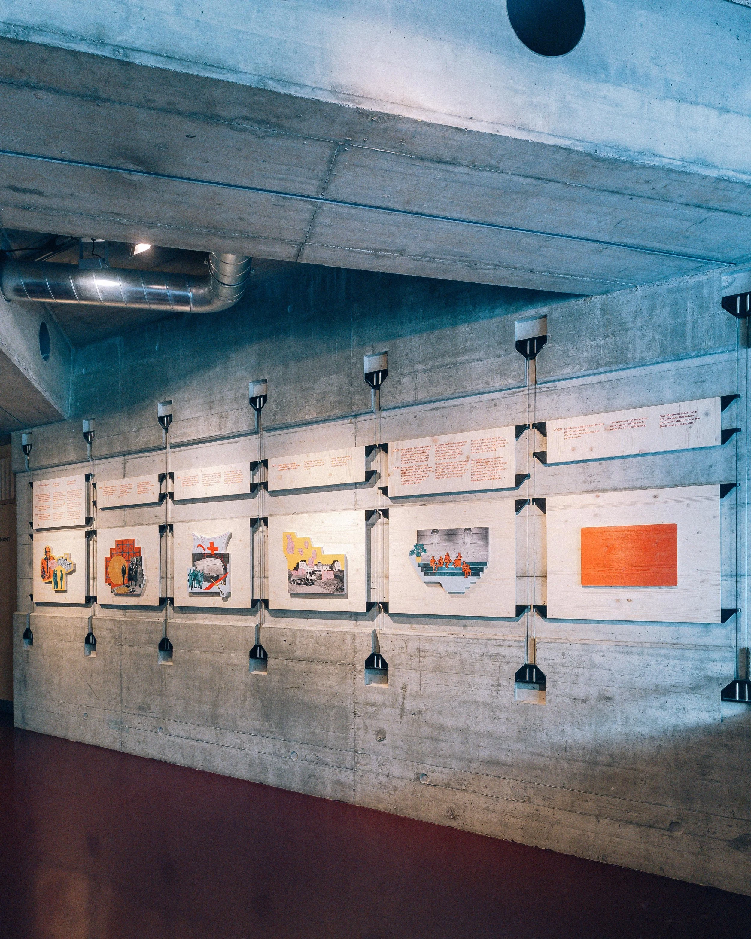Fresque historique du Musée international de la Croix-Rouge, panneaux en bois sur lesquels ont été imprimés visuels et textes racontant l'histoire du musée, suspendus à l'aide d'un système d'accroche dans un mur en béton.