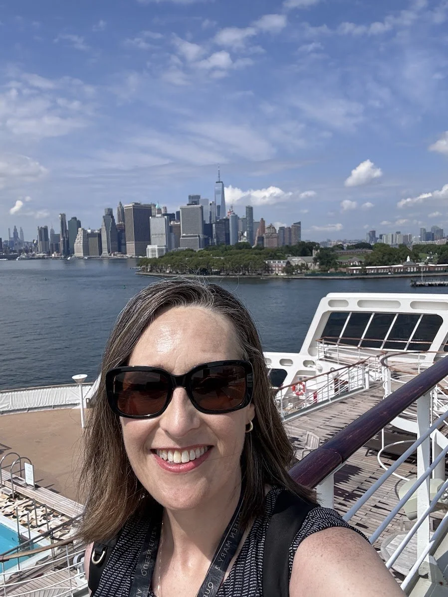 Stephanie Ng, PenguinsPreferred, poses for a picture on board the Queen Mary 2 with the New York City skyline behind her.