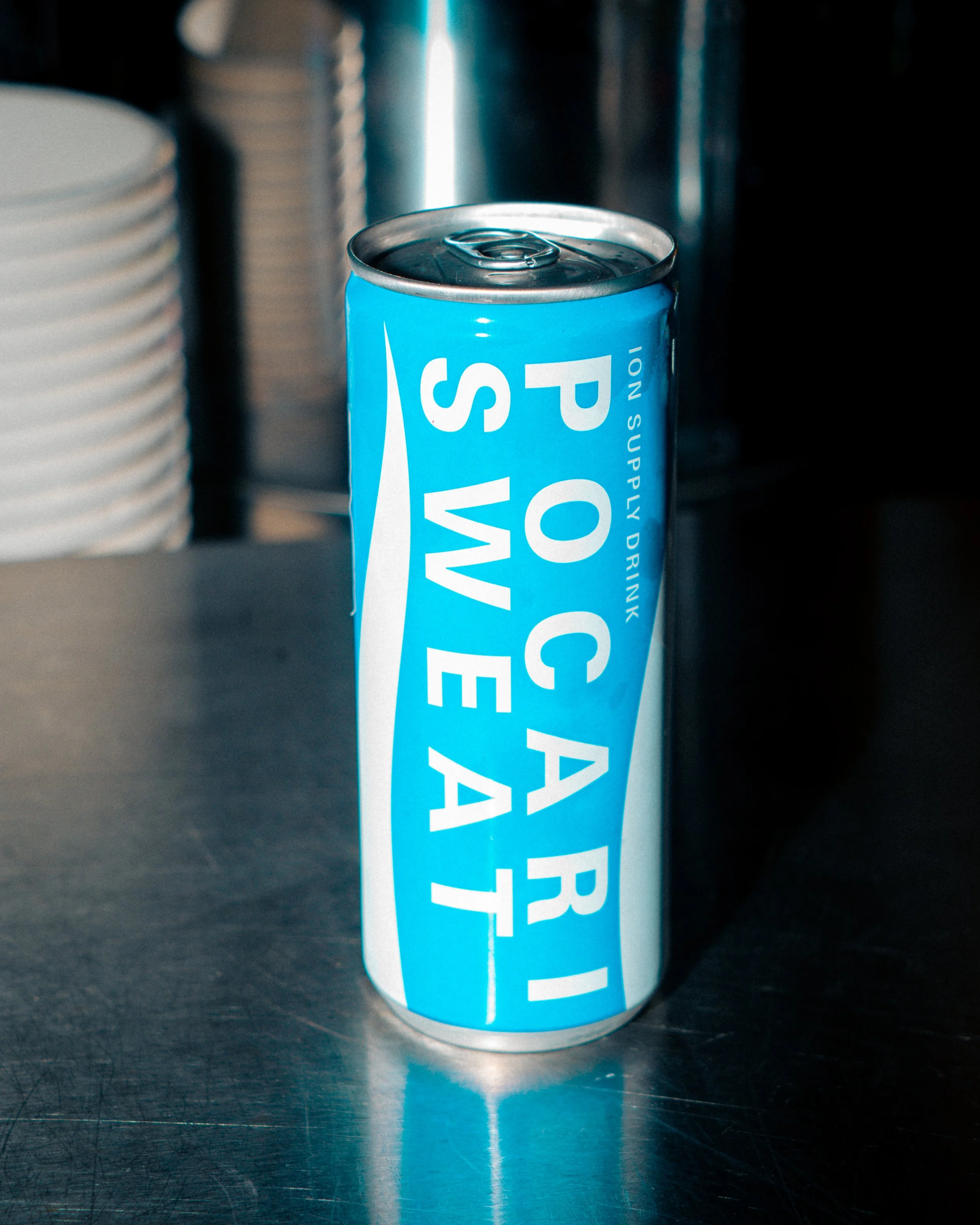 Close-up of an unopened Pepsi can with a blue label, sitting on a metallic surface with a blurred background.