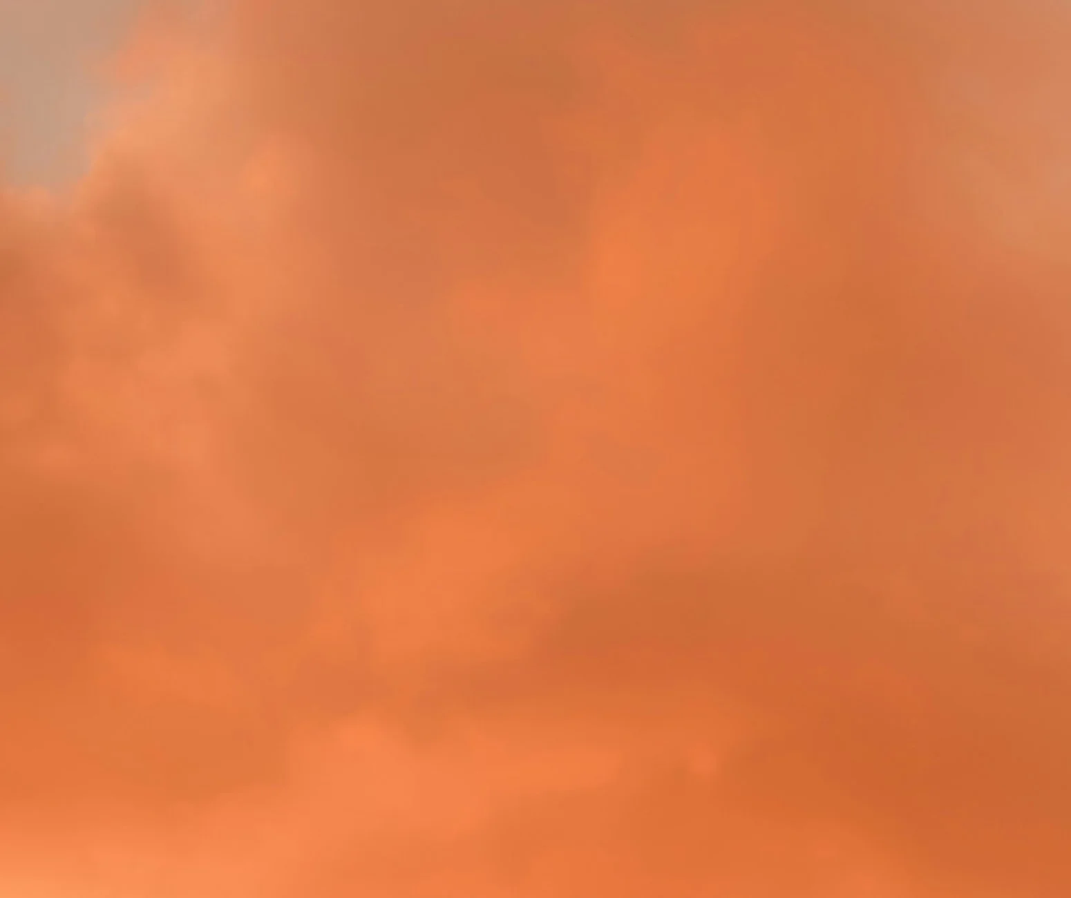 Feine Wolken vor orangefarbenem Himmel.