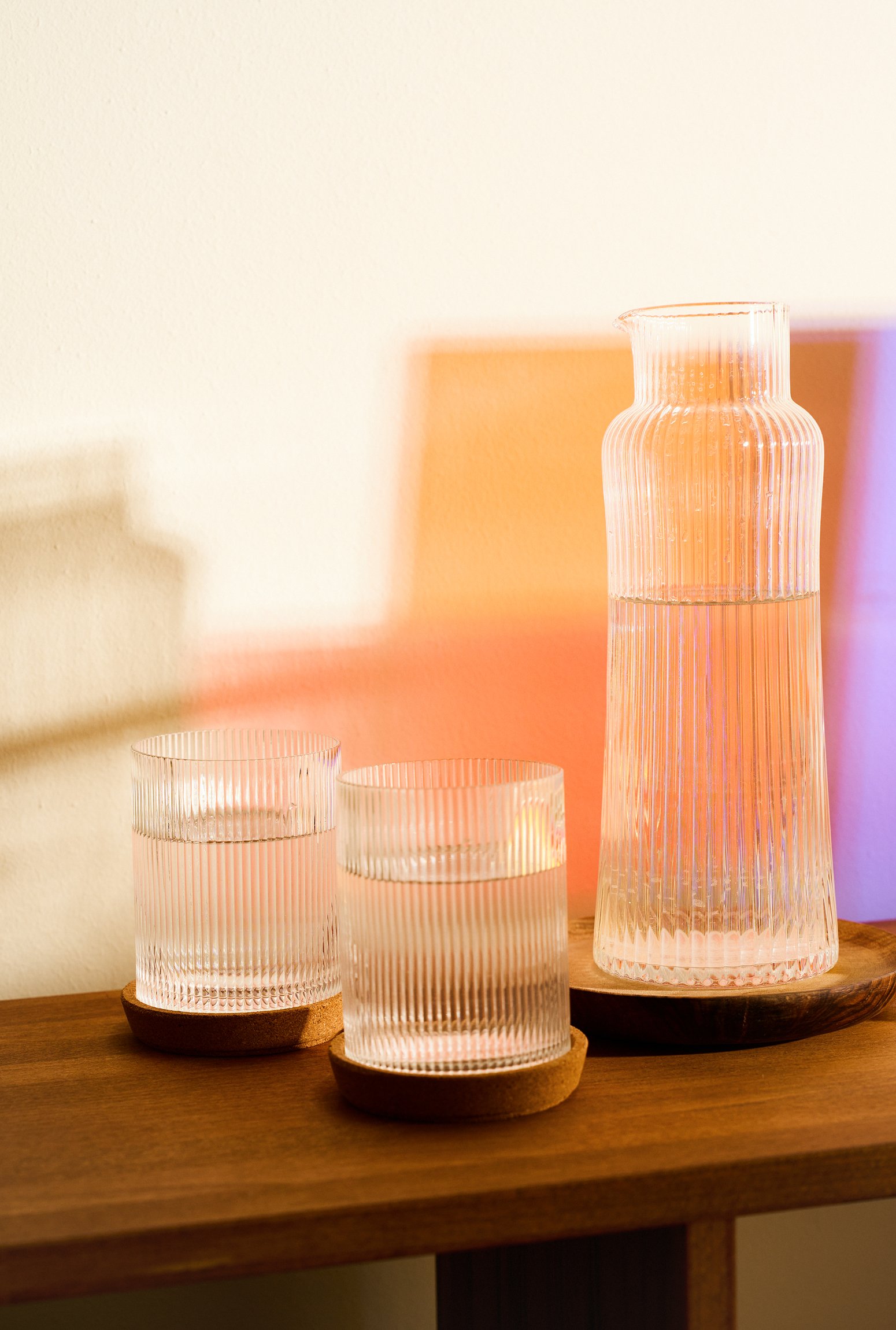 Karaffe mit zwei Wassergläsern vor der bunten Designerlampe im Therapieraum der Privatpraxis Anna Anft.