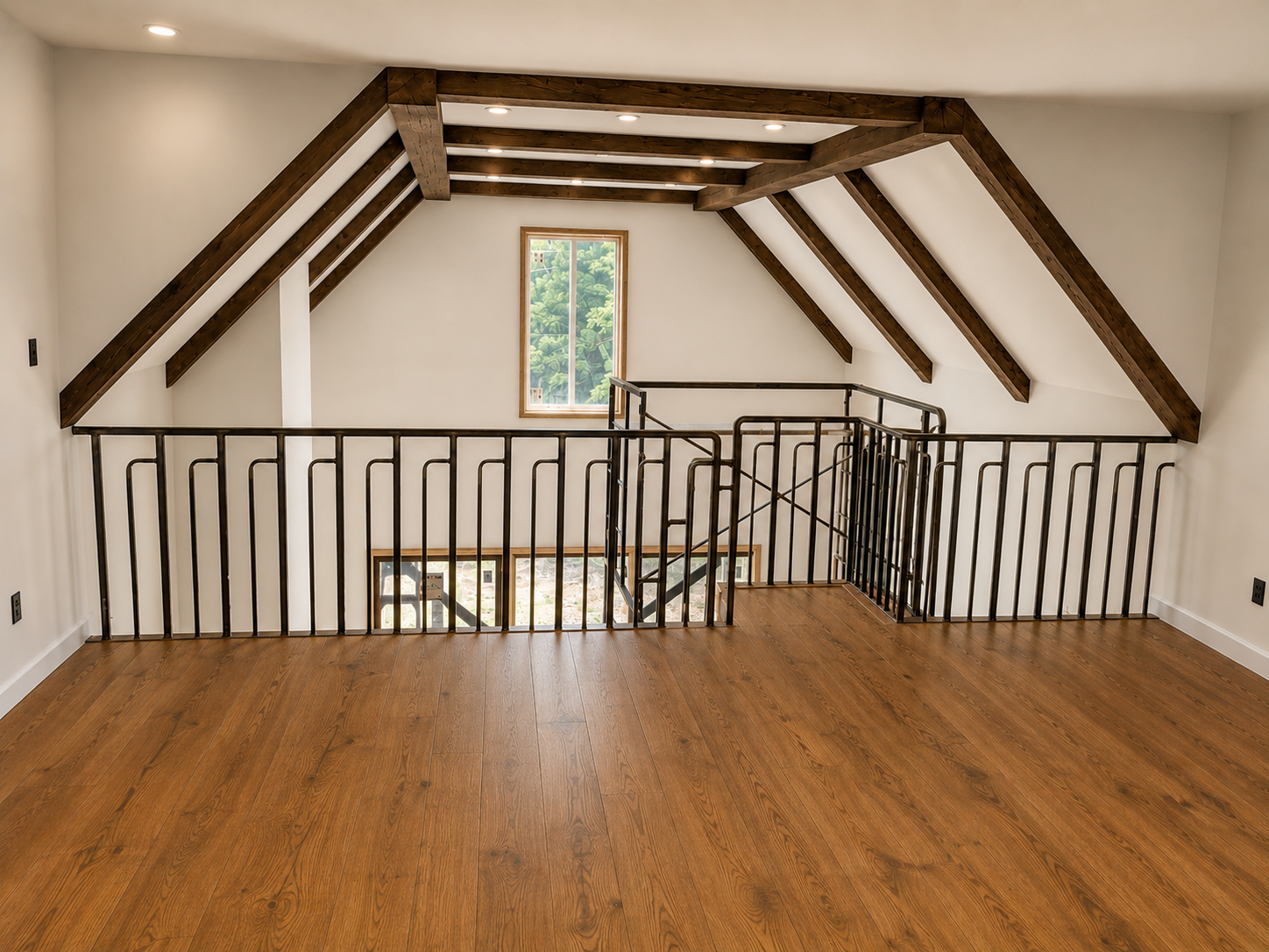 Empty loft space with wooden floor, white walls, exposed dark wooden beams, and black metal railing around the staircase opening, with a small window showing greenery outside.