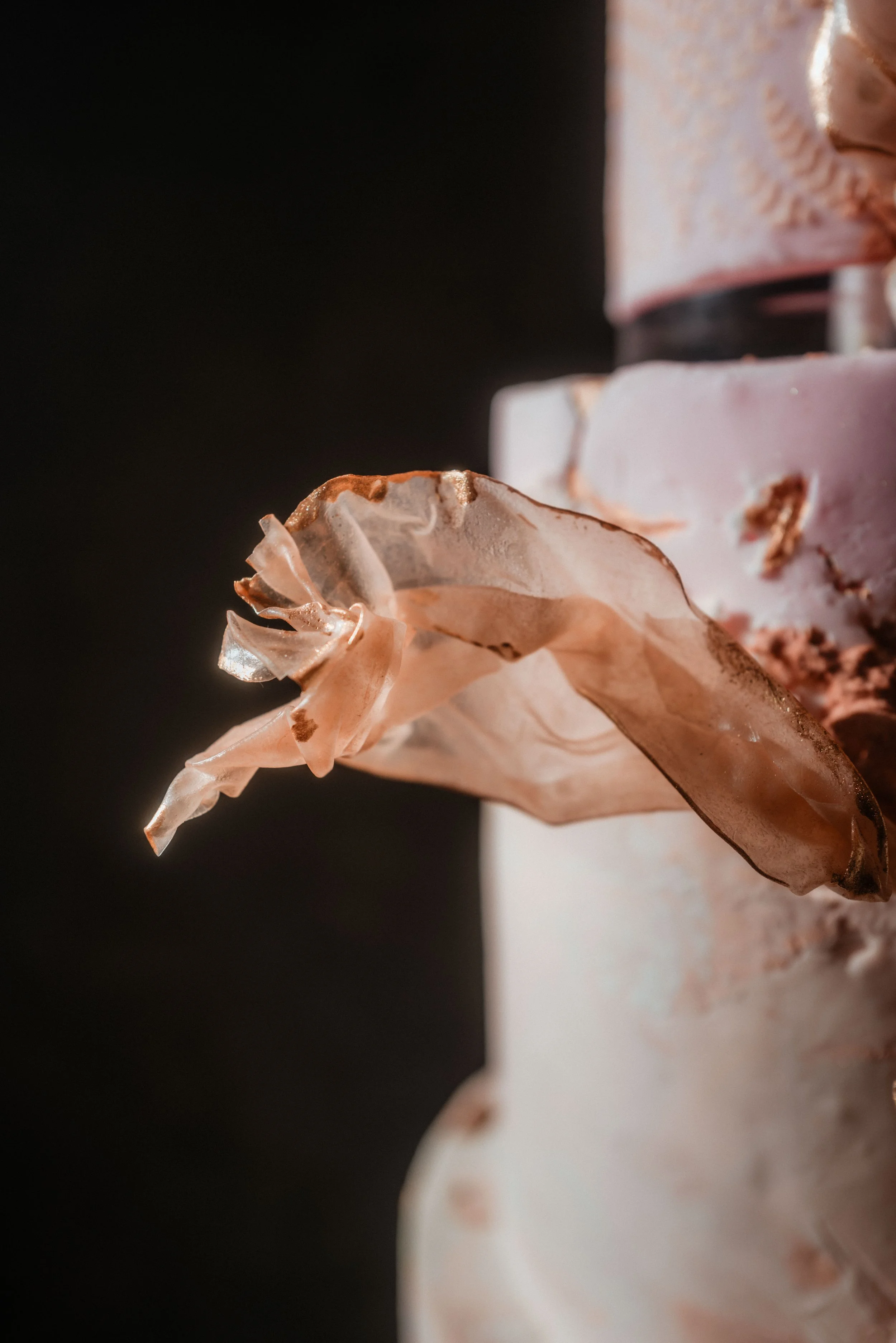 Close-up of handcrafted rice paper botanical details on a contemporary luxury wedding cake with textured finishes and soft blush tones.