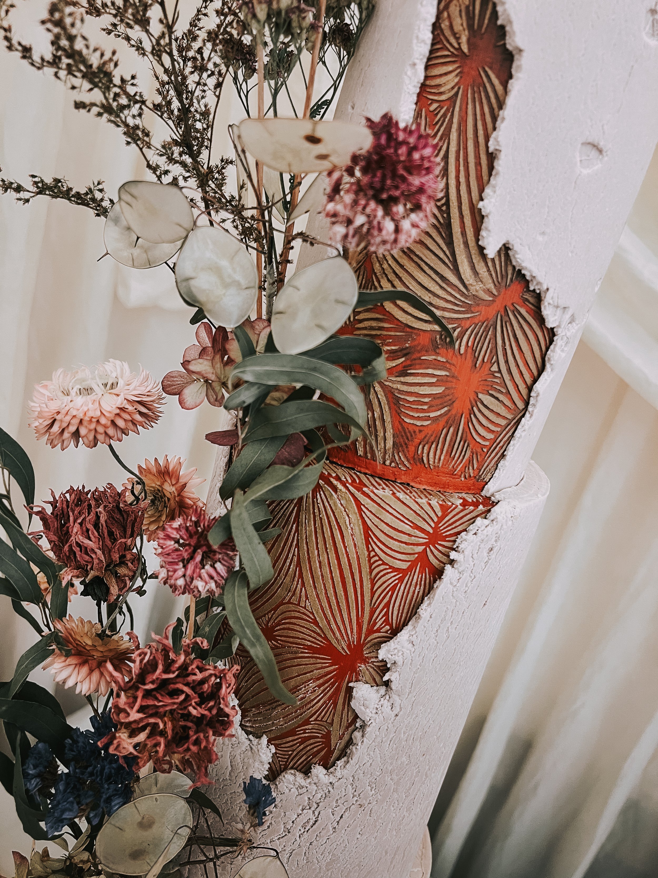 Close-up detail of a wedding cake with hand-painted botanical patterns, textured fondant and dried flowers.