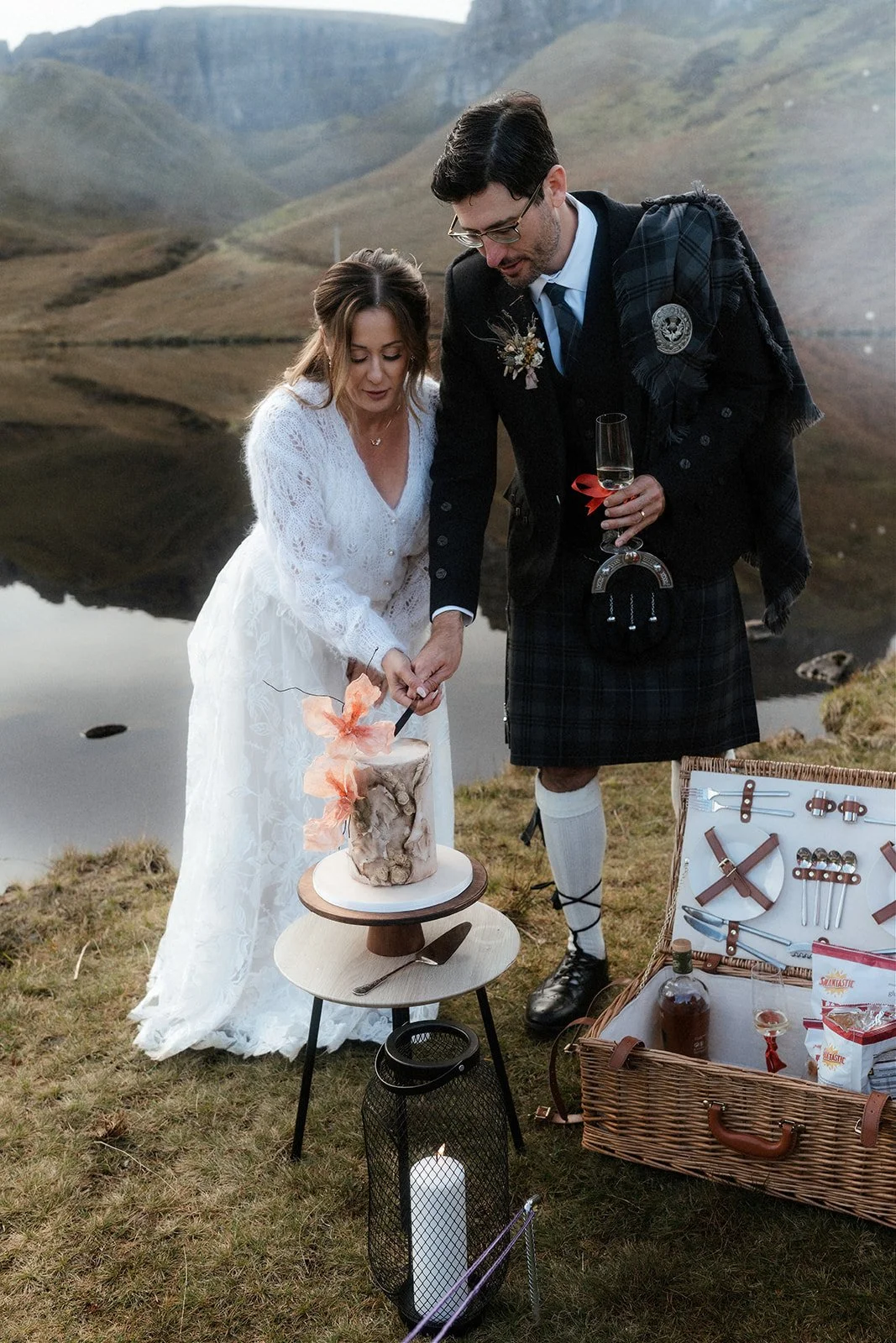 Couple cutting elopement wedding cake beside Loch Langaig on the Isle of Skye, in the Scottish Highlands.