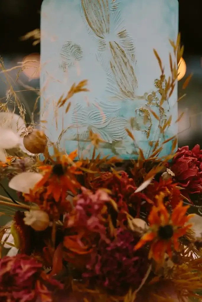 Close-up details of duck egg blue tier, with hand-painted botanical details and autumnal dried flowers at Glencruitten House in Oban.