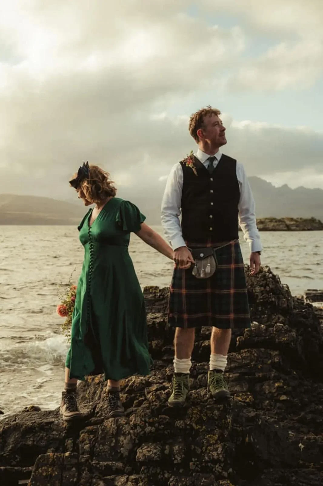 Couple holding hands beside the sea at Dunscaith Castle on the Isle of Skye after their intimate elopement.