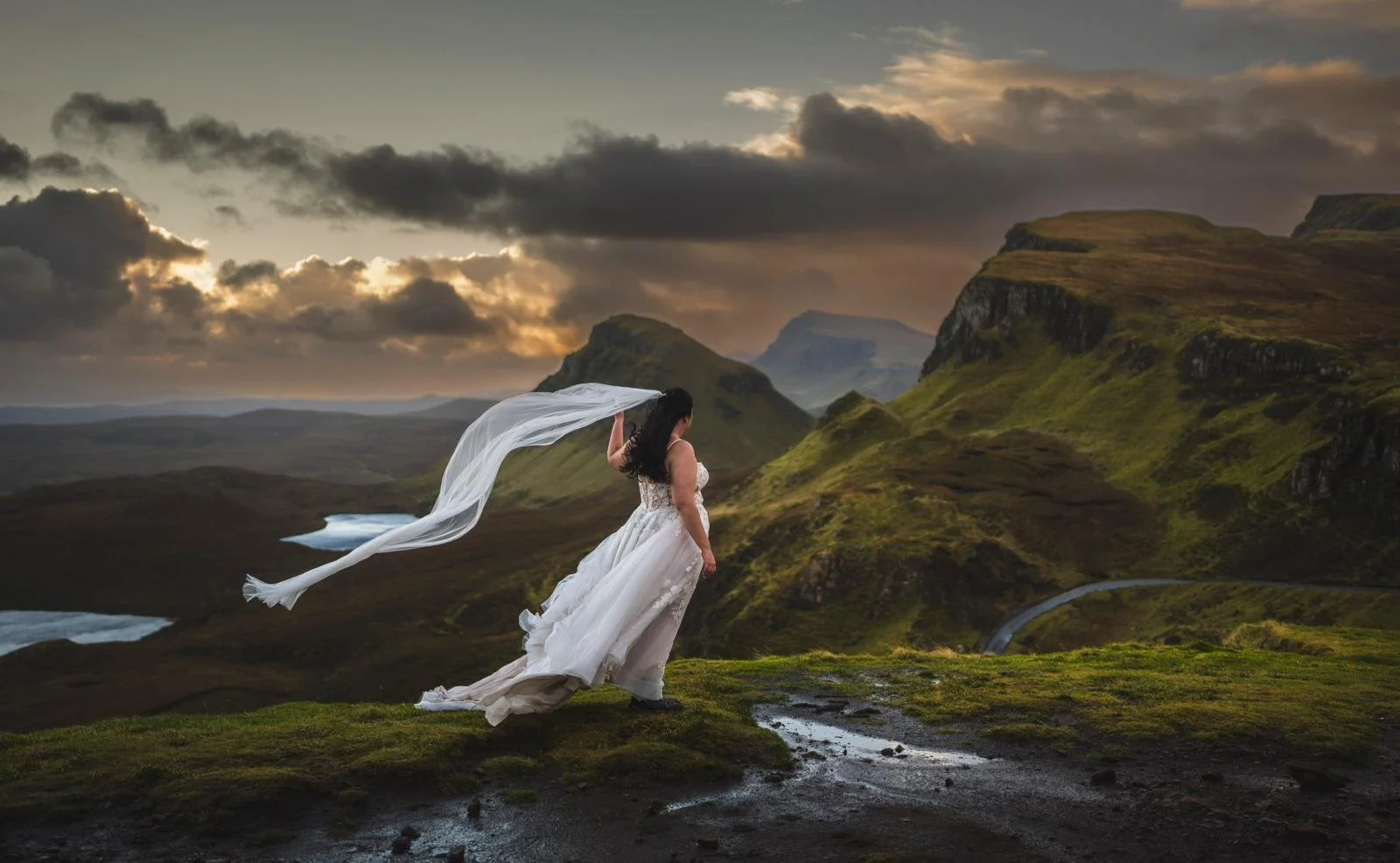 Bride standing at the Quiraing on the Isle of Skye during dramatic Highland storm with her veil blowing in the wind.