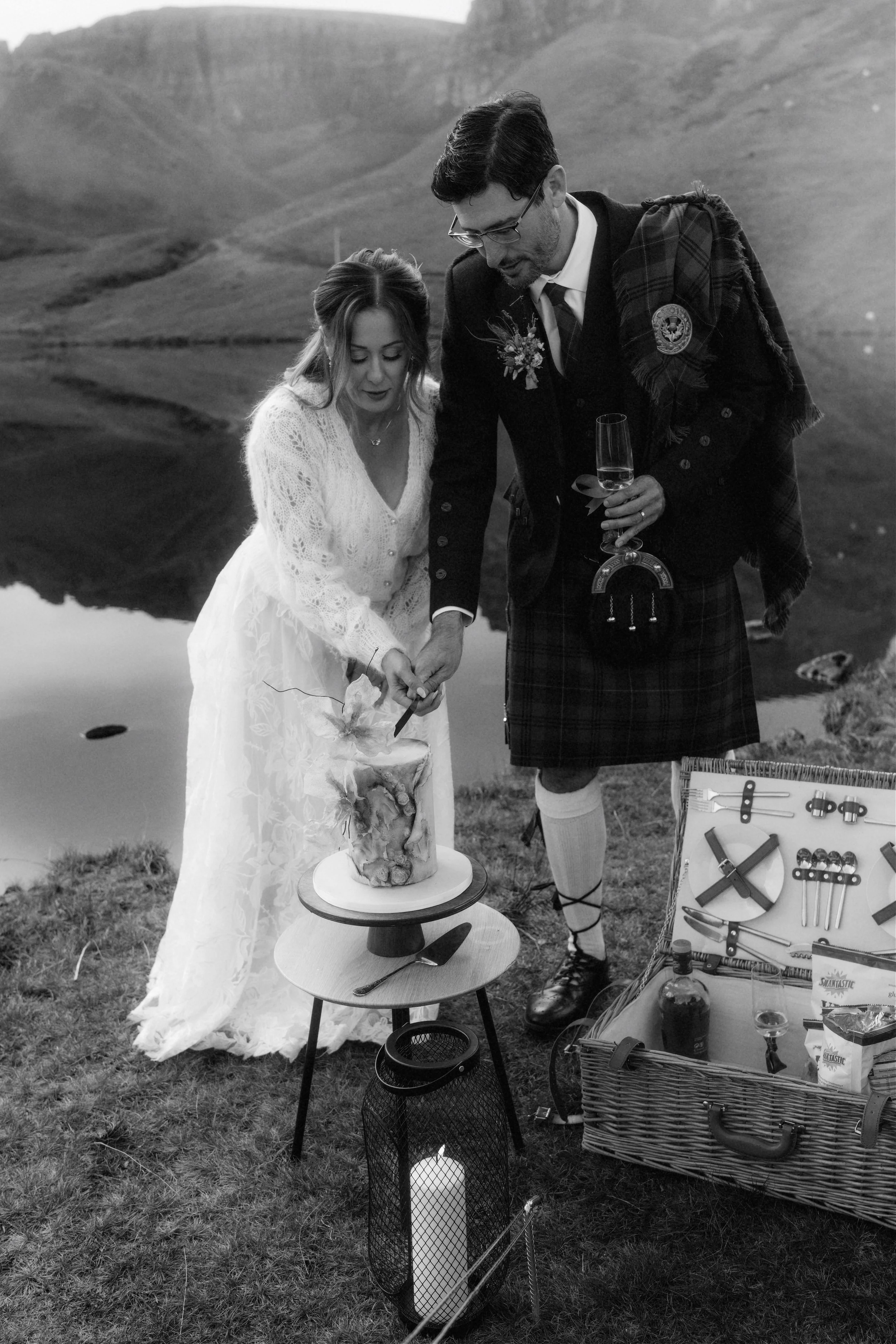 Couple cutting their wedding cake during an intimate elopement at Loch Langaig, Isle of Skye, surrounded by dramatic Highland scenery.