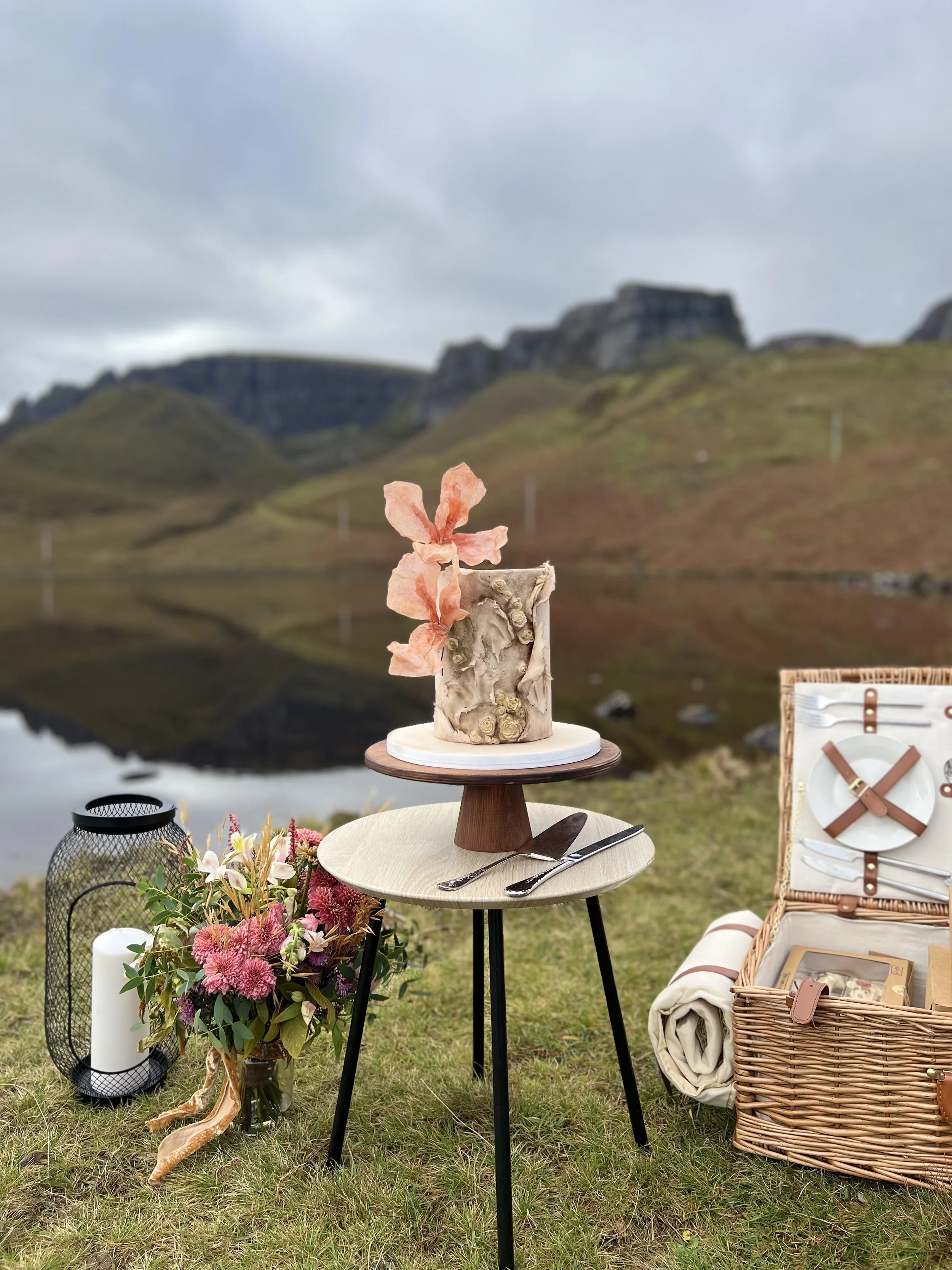Handcrafted wedding cake and picnic setup with Loch Langaig, Skye landscape backdrop