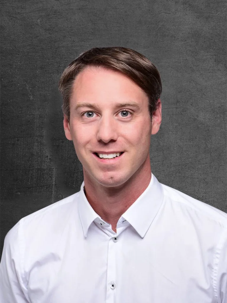Ein junger Mann mit braunem Haar trägt ein weißes Hemd vor einem grauen Hintergrund (Christoph Tremmel, Serviceassistent Autohaus KELLER).