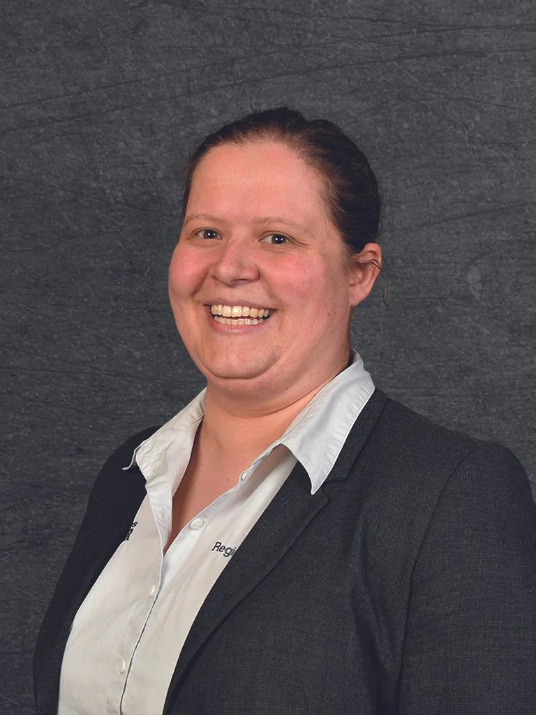 Porträt einer lächelnden Frau in formeller Kleidung vor dunklem Hintergrund (Regine Darlapp, Serviceassistentin Autohaus KELLER).
