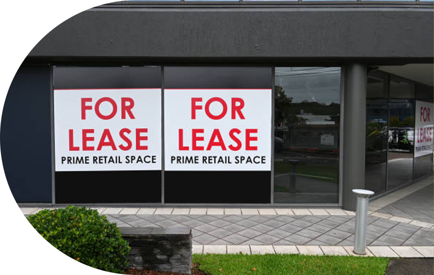 A photograph depicting a building with signs on the windows stating “For Lease, Prime Retail Space”.