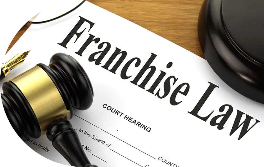 A photograph depicting a gavel and pen resting on a paper that says “Franchise Law”.