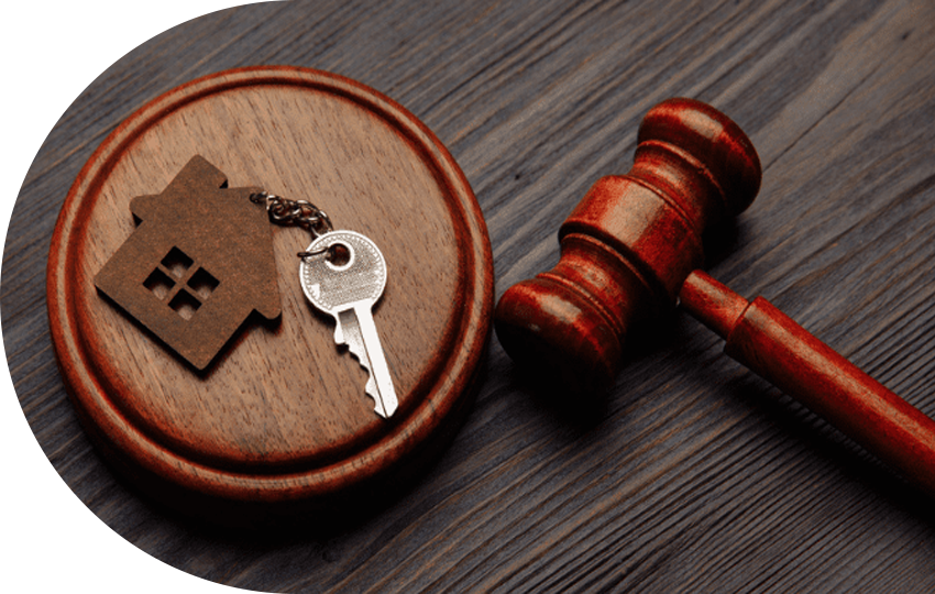 A photograph depicting a key attached to a keychain that looks like a house, as well as a gavel.