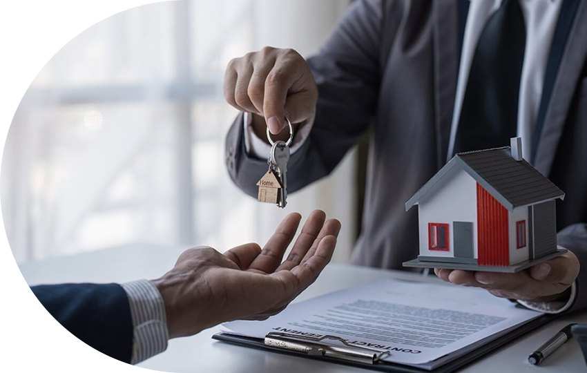 A photograph depicting a person handing a key and a miniature-sized house to another person.