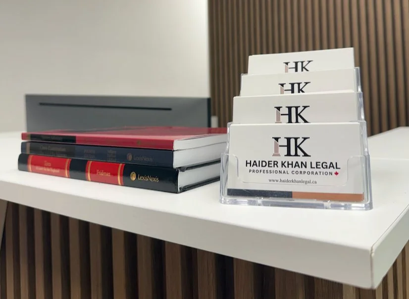A photograph of the Haider Khan Legal office, containing legal books as well as business cards.
