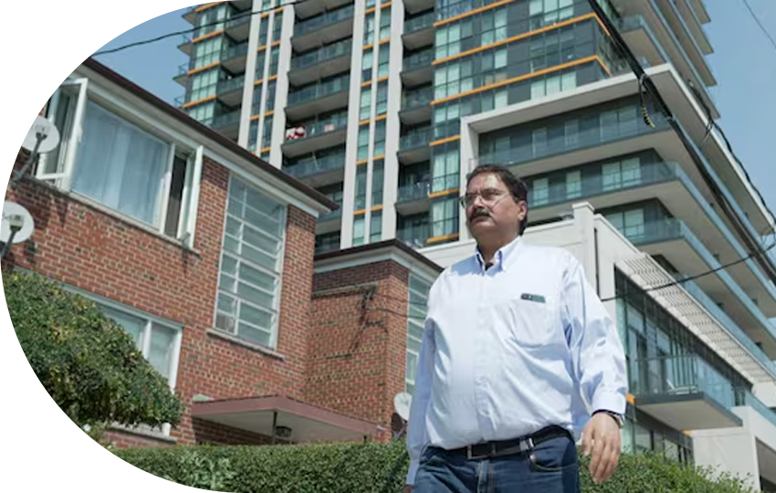 A photograph depicting a man standing outside near various residential buildings.