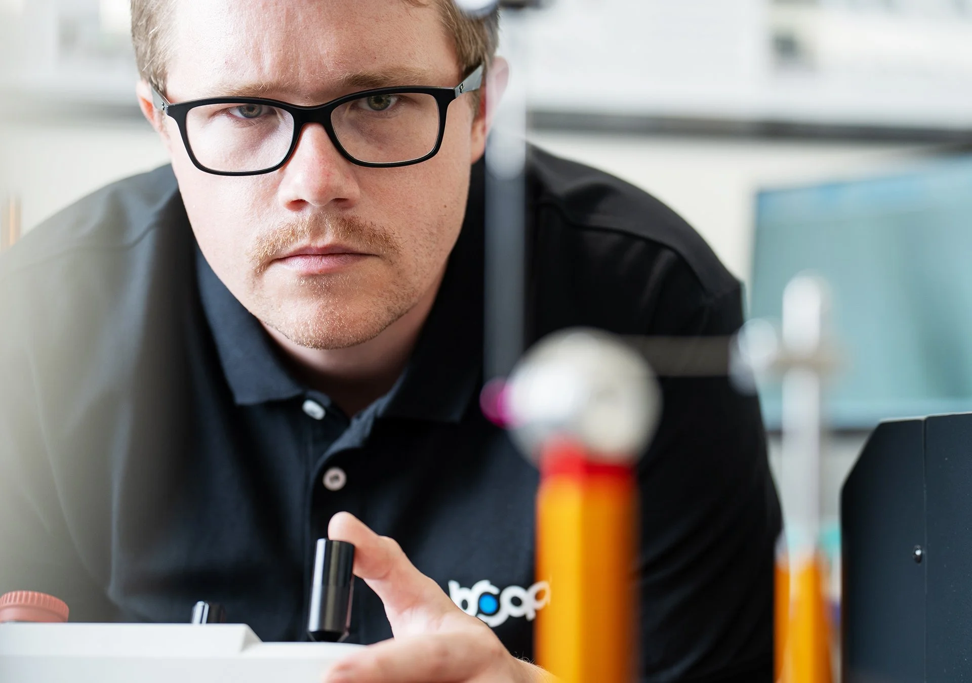 En man med glasögon som arbetar med ett labb, med fokus på mätutrustning för cnc-tillverkning.