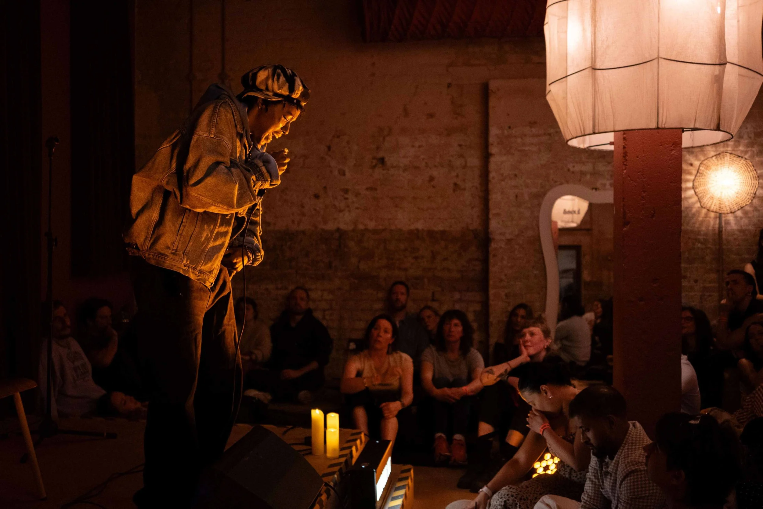 Woman shares her story at a RAW uncensored storytelling night in London in a dimly lit room as people sit on the floor and listen