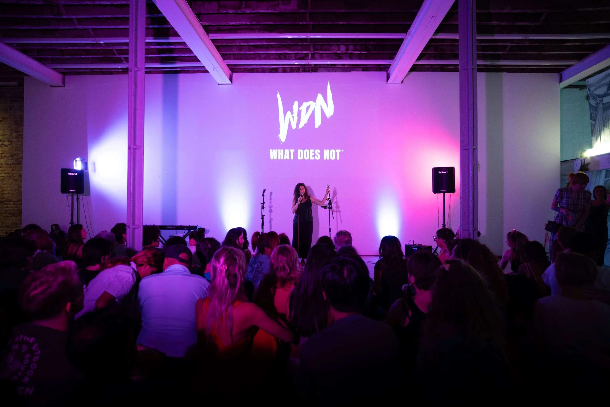Founder, Christine, at RAW uncensored storytelling night welcomes the audience as the WDN logo is projected on the background