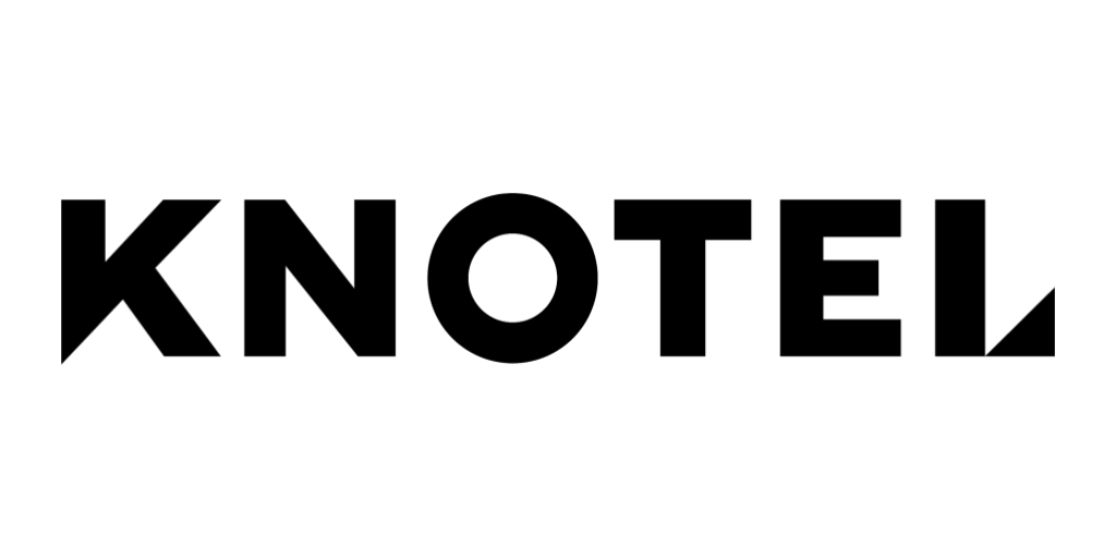 A black Christmas tree with glittery silver ornaments and a star on top, illuminated against a dark background.