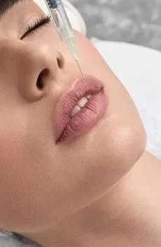 Close-up of a woman receiving a facial injection with a syringe near her lips.