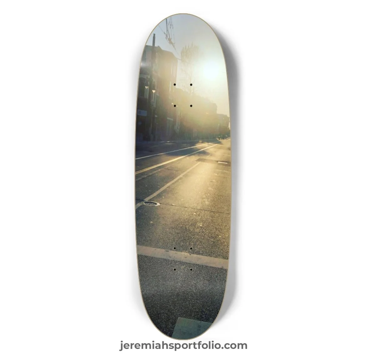 Skateboard deck with a reflective surface showing a street scene with sunlight, buildings, and trees.