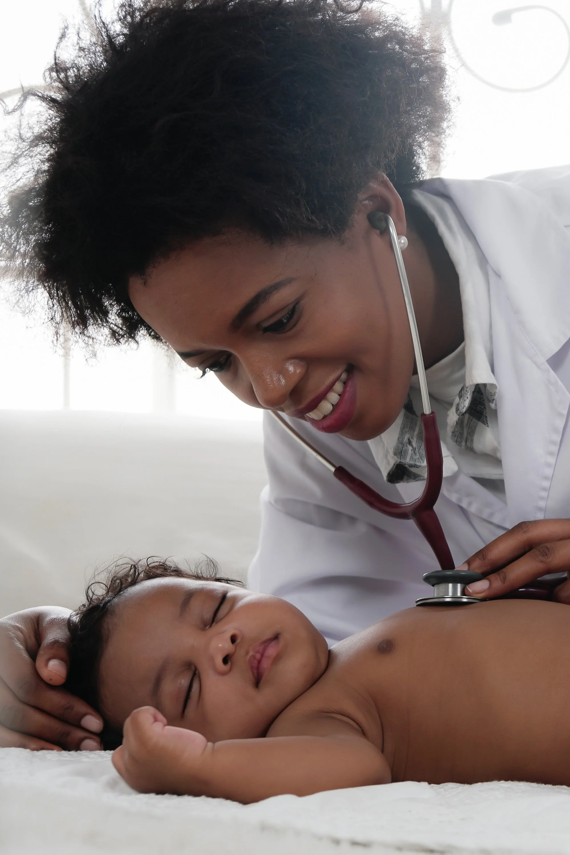 doctor performing checkup on sleeping infant