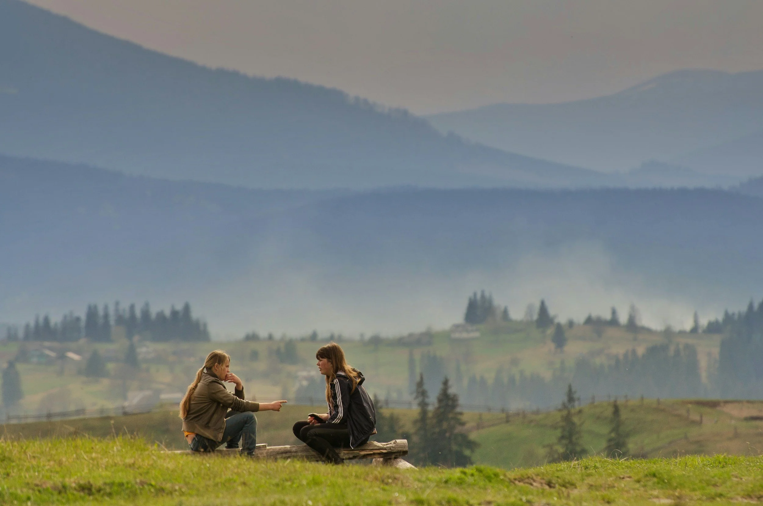 two women talking in nature mountain background