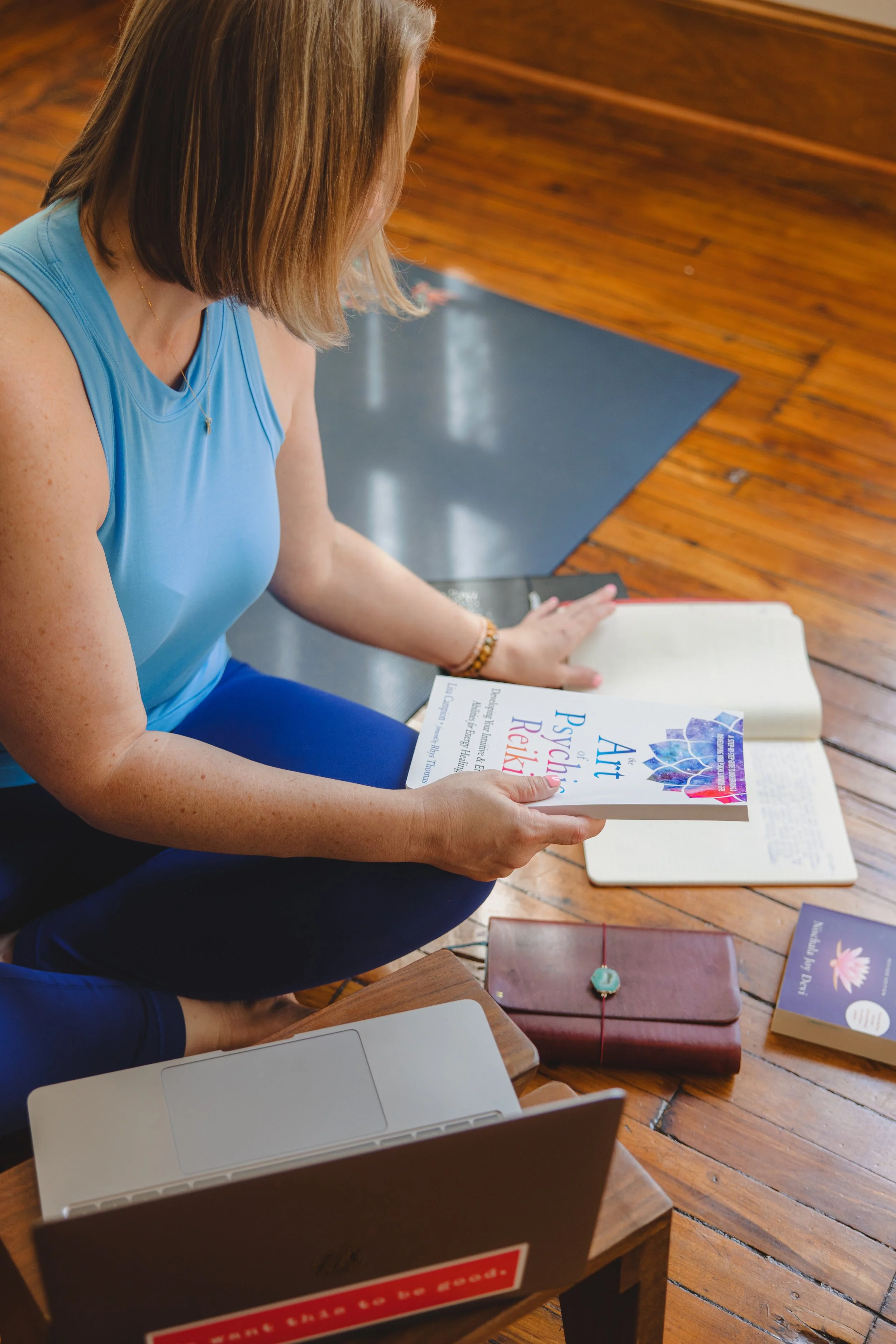 image of a person holding a book on reiki sitting on the floor at a computer