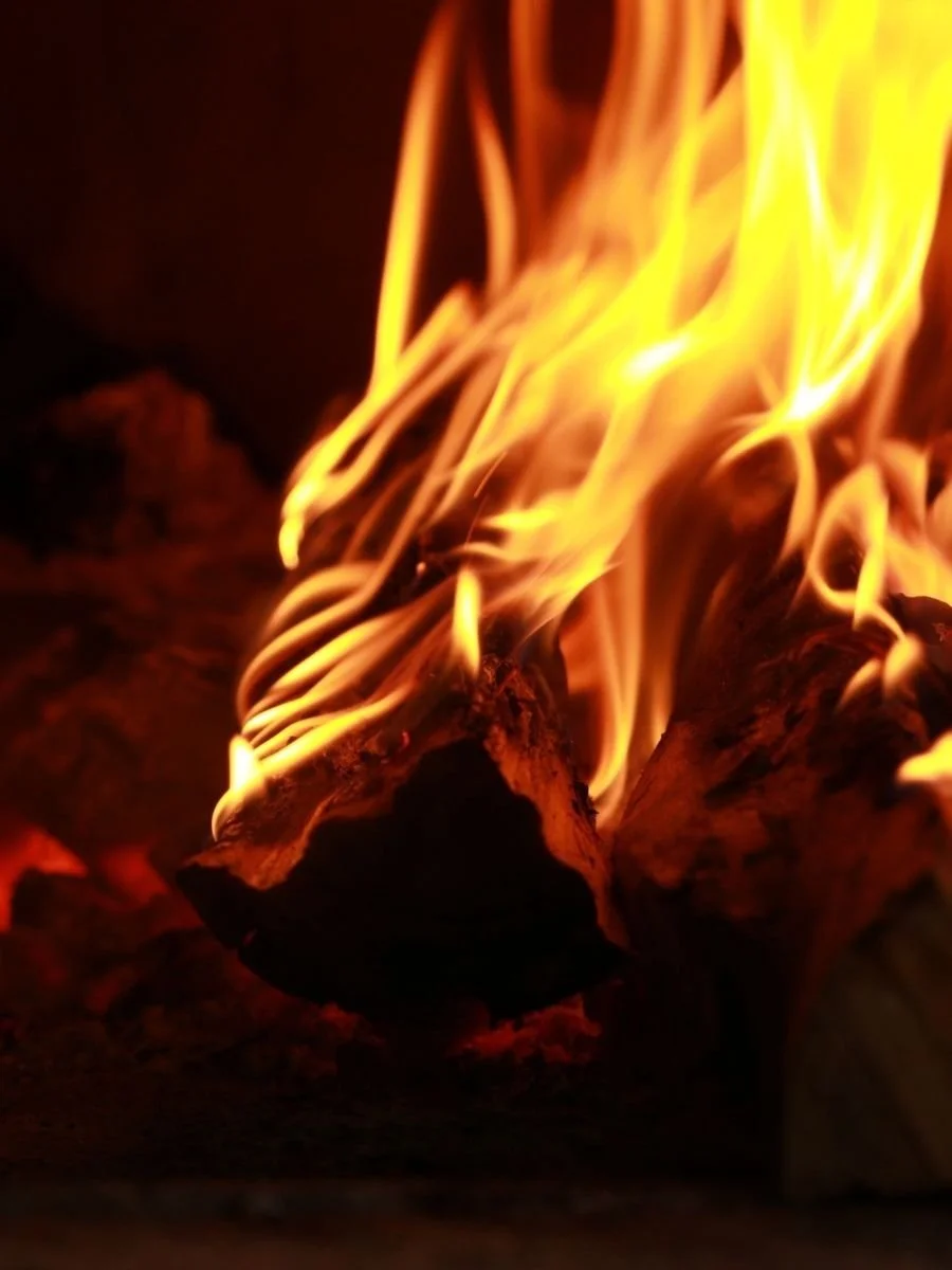 Close-up of burning logs with orange and yellow flames in a fire.