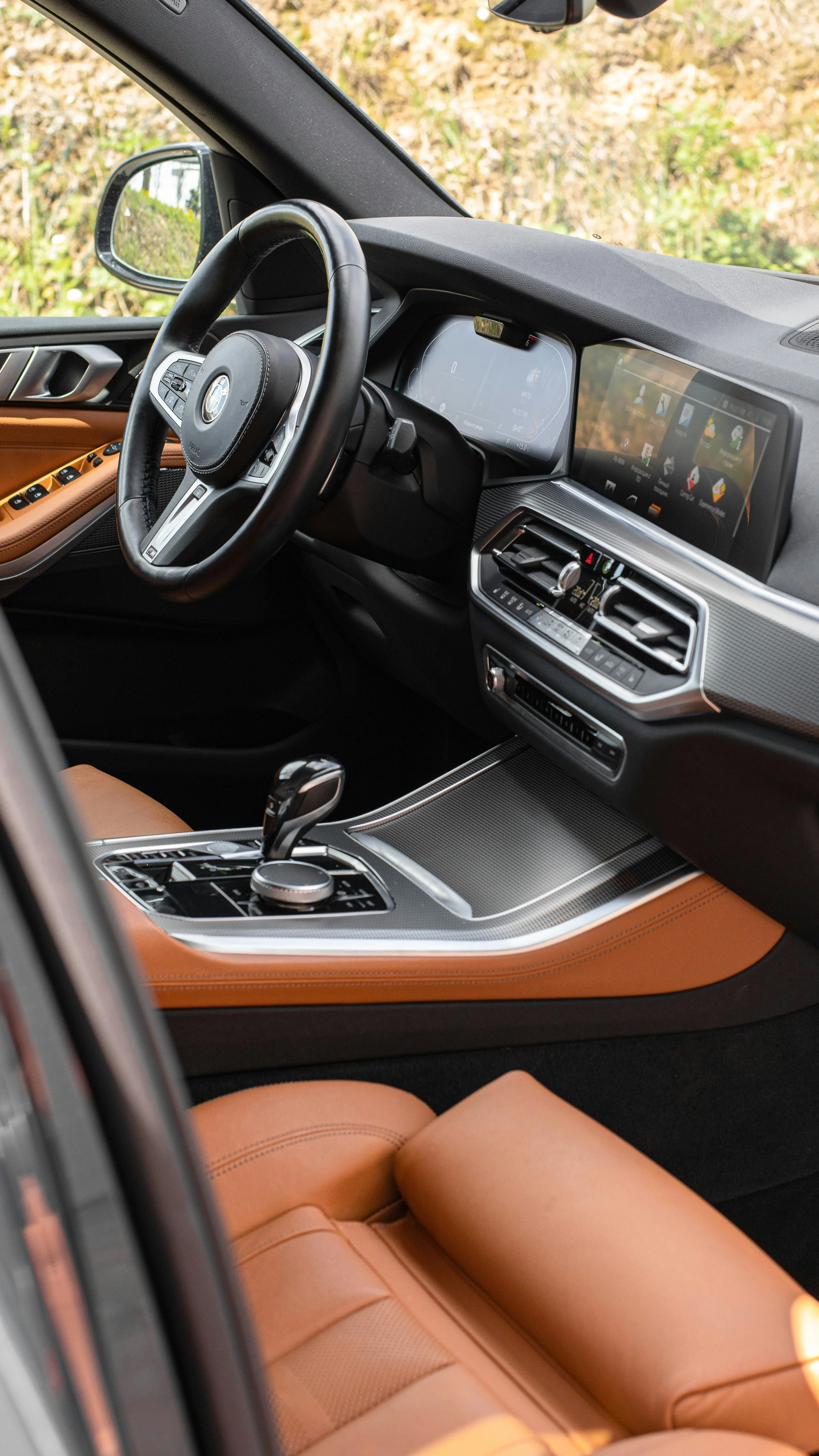 Inside view of a luxury car's interior showing a leather seat, dashboard with a digital display, and a steering wheel with controls.