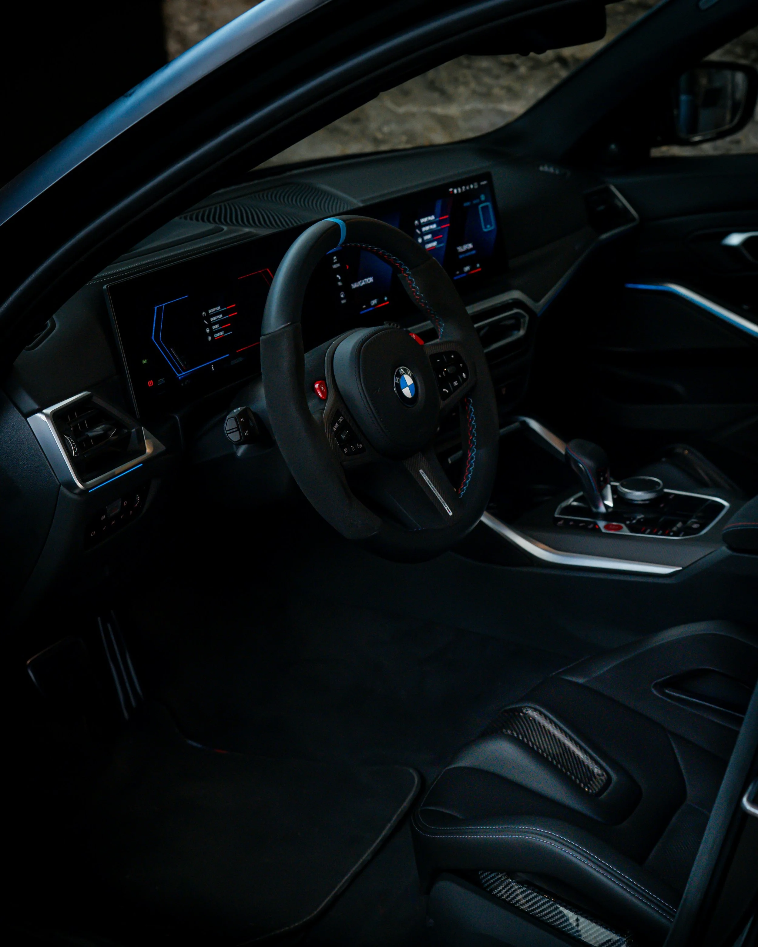 Interior of a BMW car showing the dashboard, steering wheel, and center console, with digital displays and control buttons.