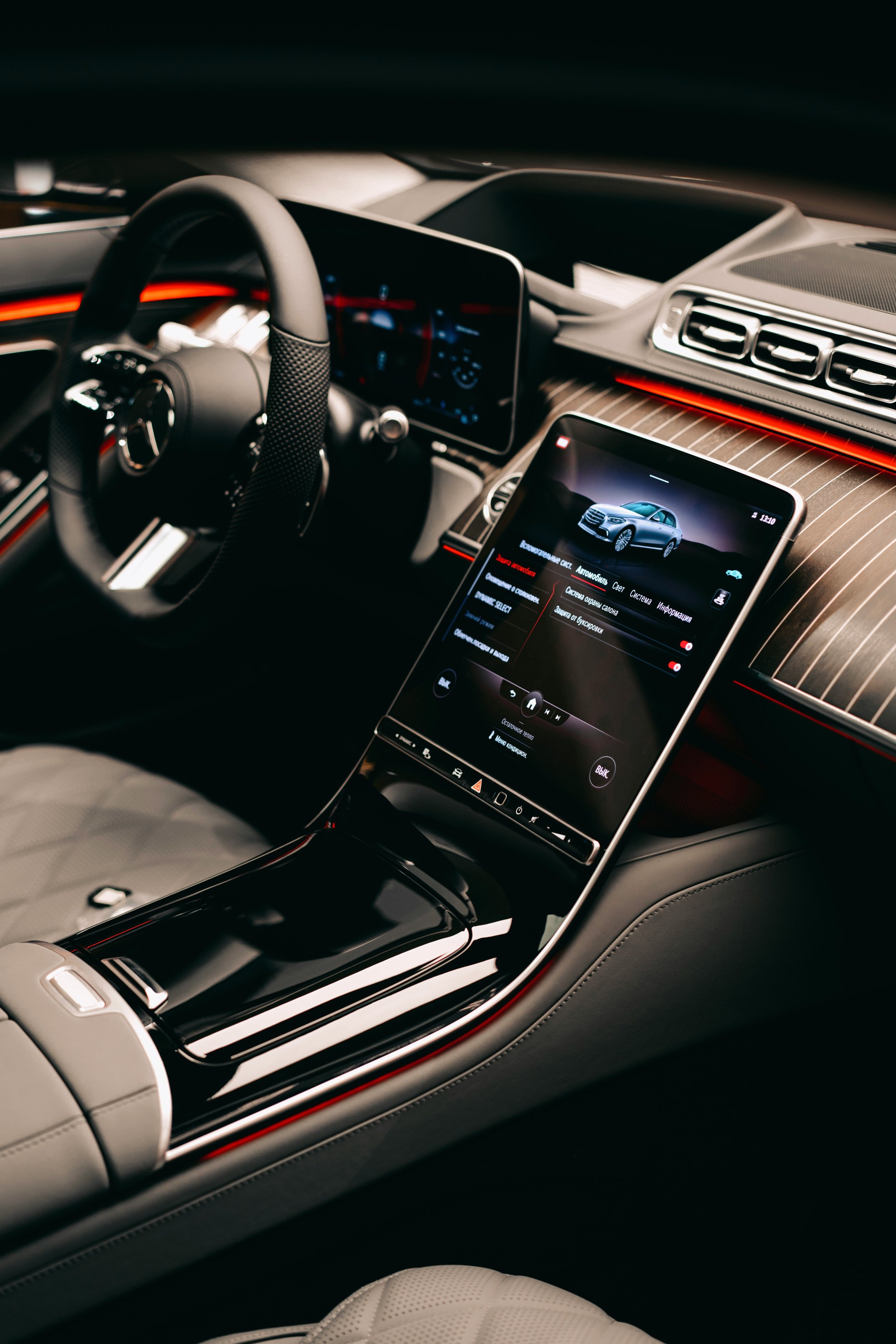 Interior of a modern luxury car showing a steering wheel, digital display, and infotainment screen with a car diagram.