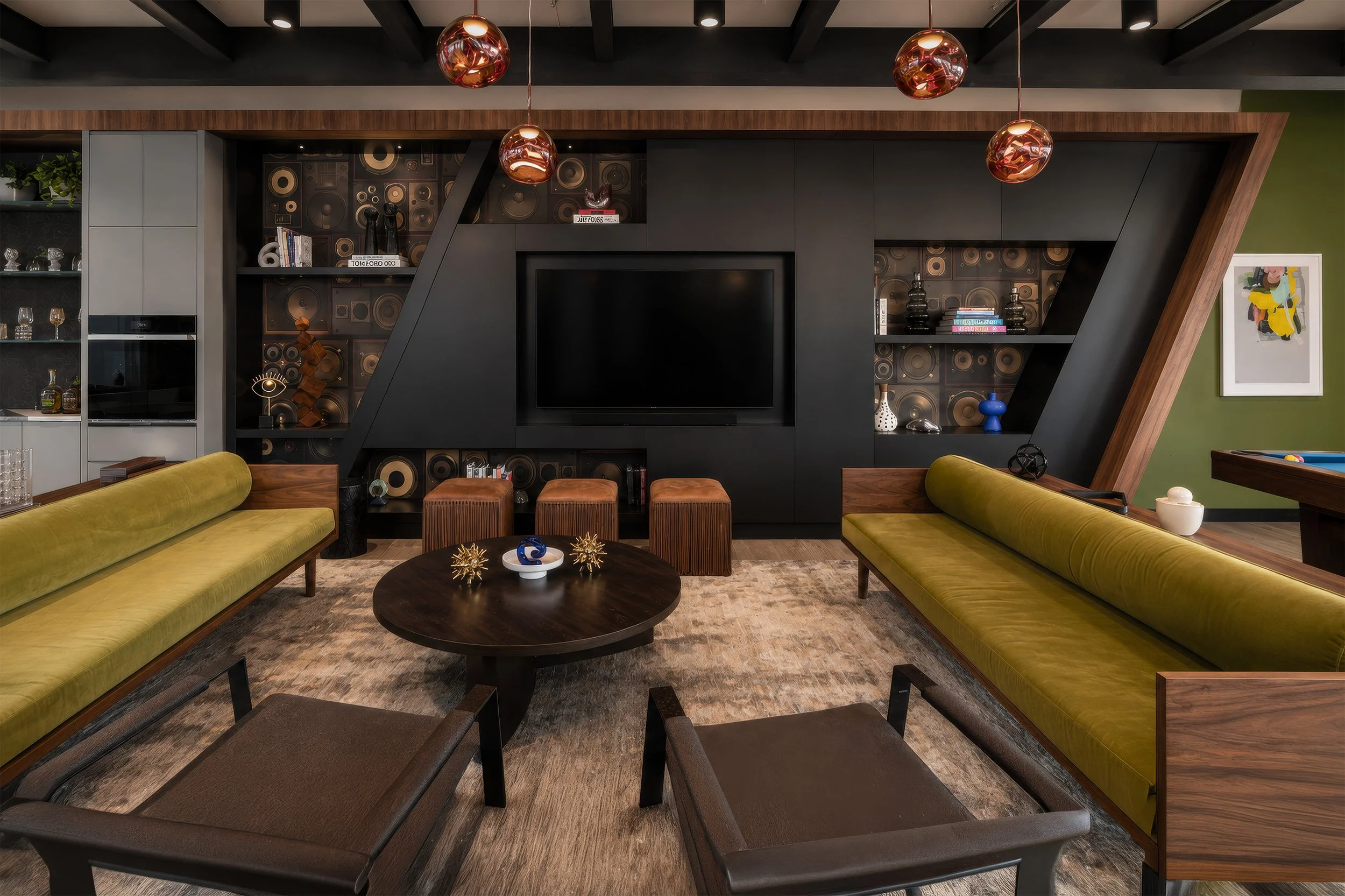 Living room with a black accent wall, wooden accents, green sofas, a round coffee table with decorative objects, and modern lighting fixtures.