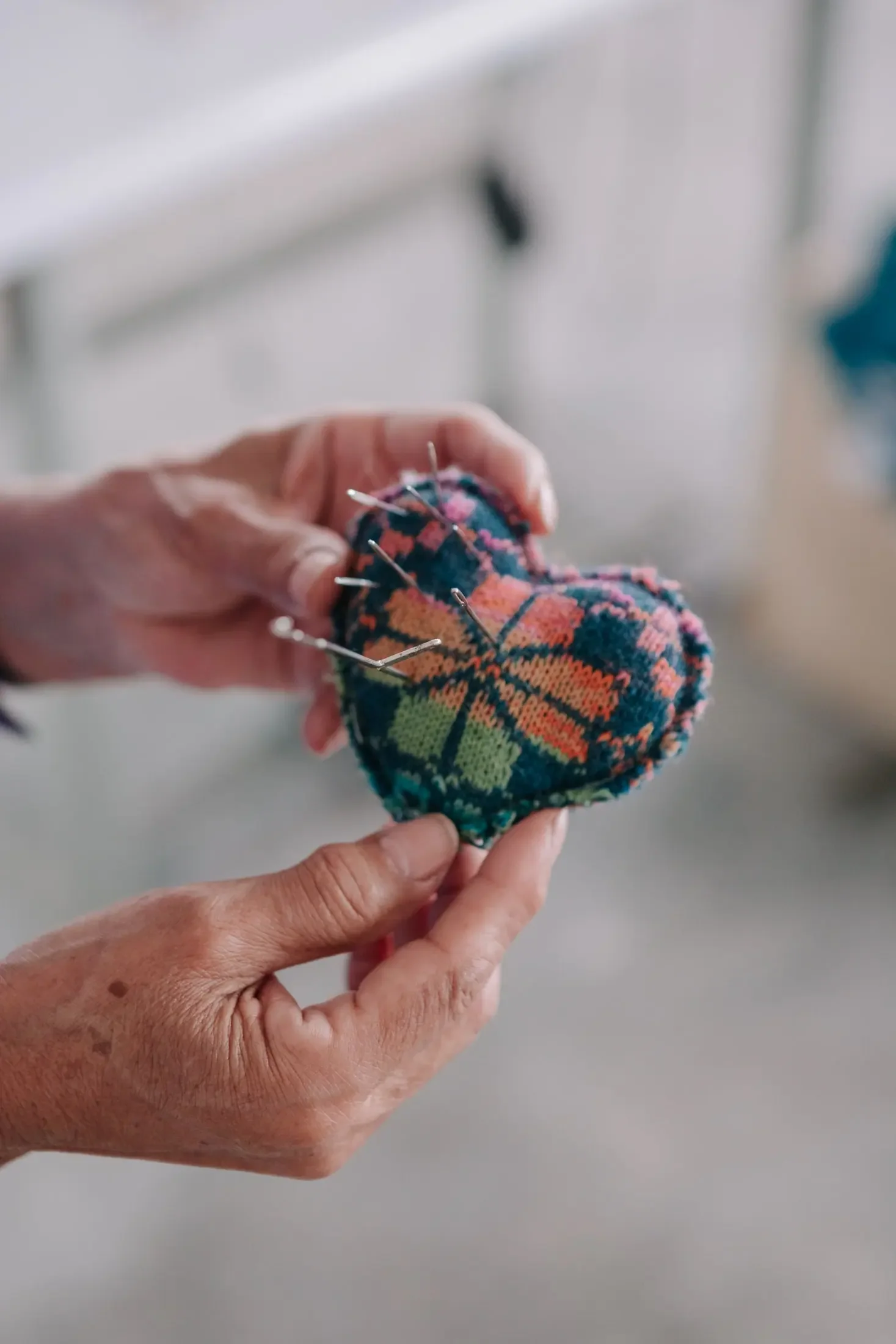 Manuela Bedford hands repairing a knitted alpaca cardigan with pins