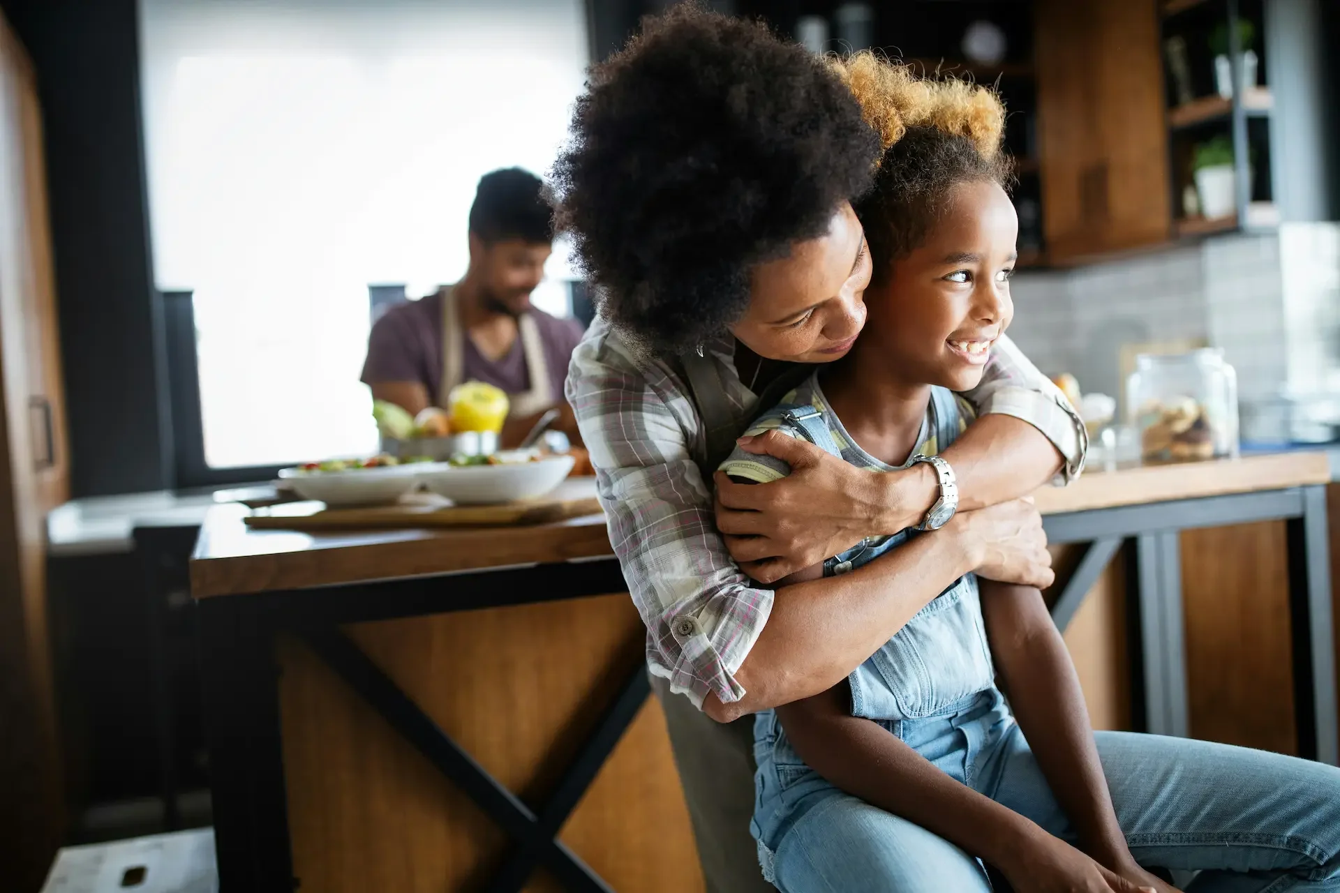 Mom hugging daughter from behind, both smiling