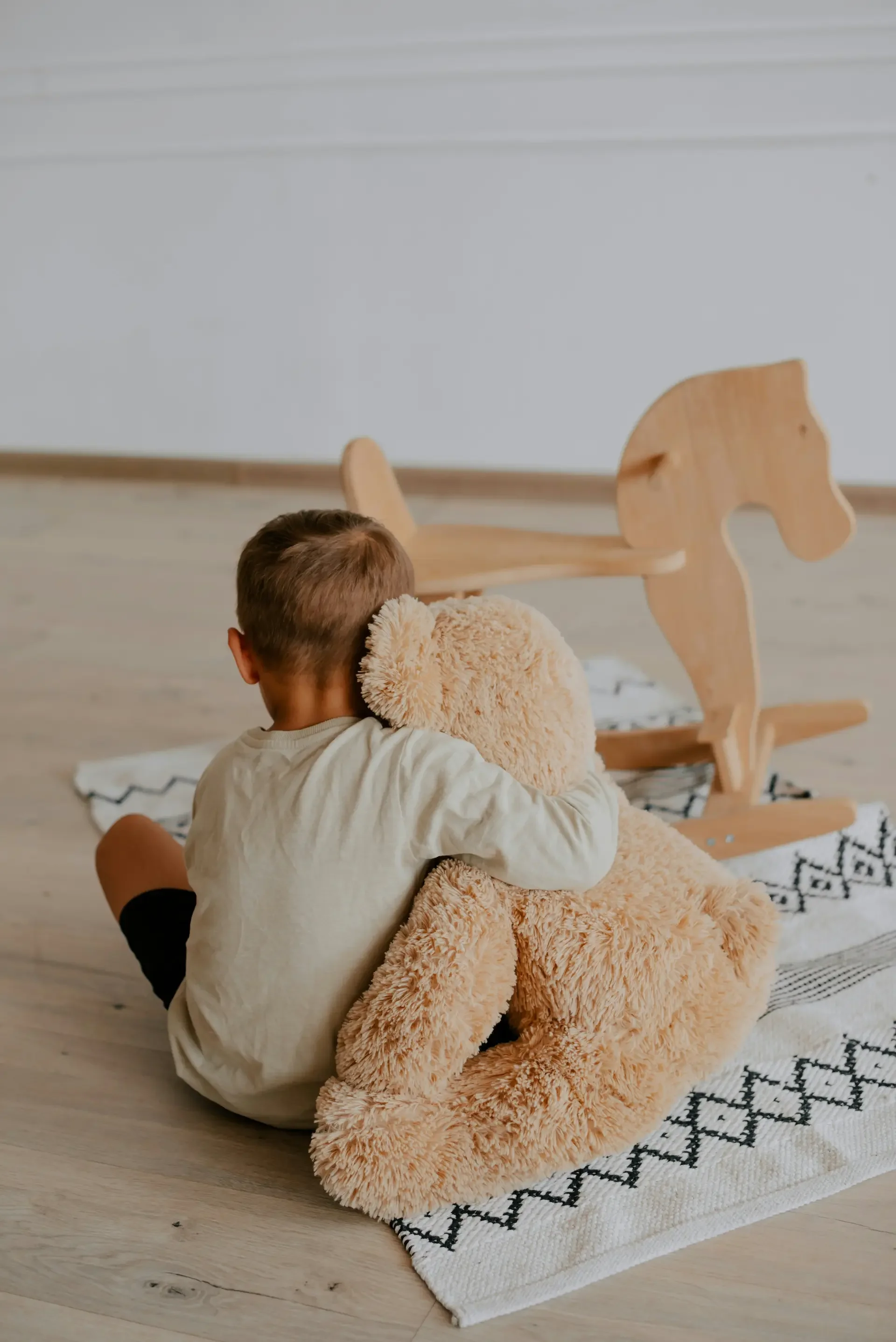 Boy sitting on floor with stuffed bear