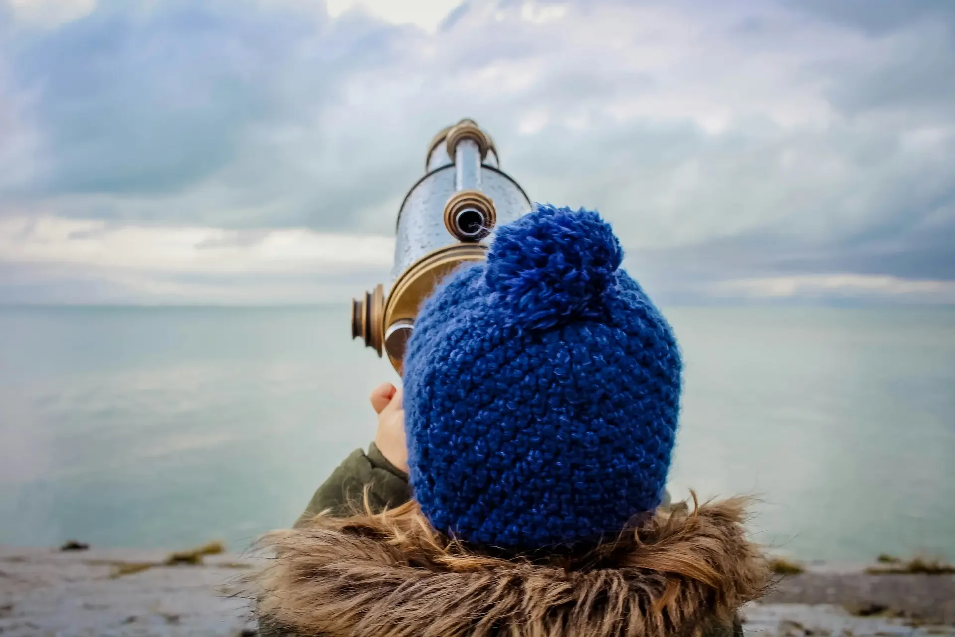 Child gazing through viewer at clouds