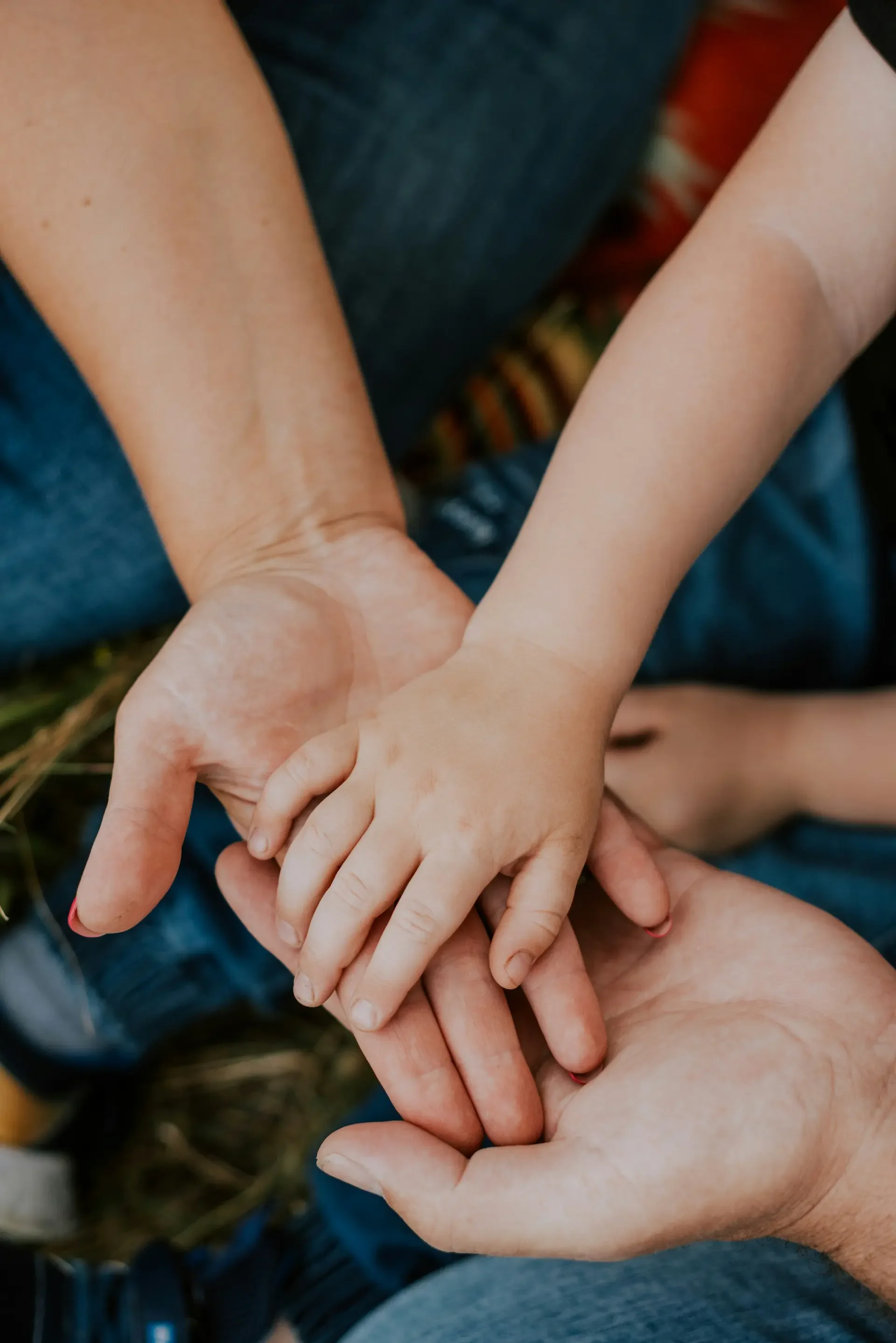 Family hands stacked, adults on bottom and toddler on top