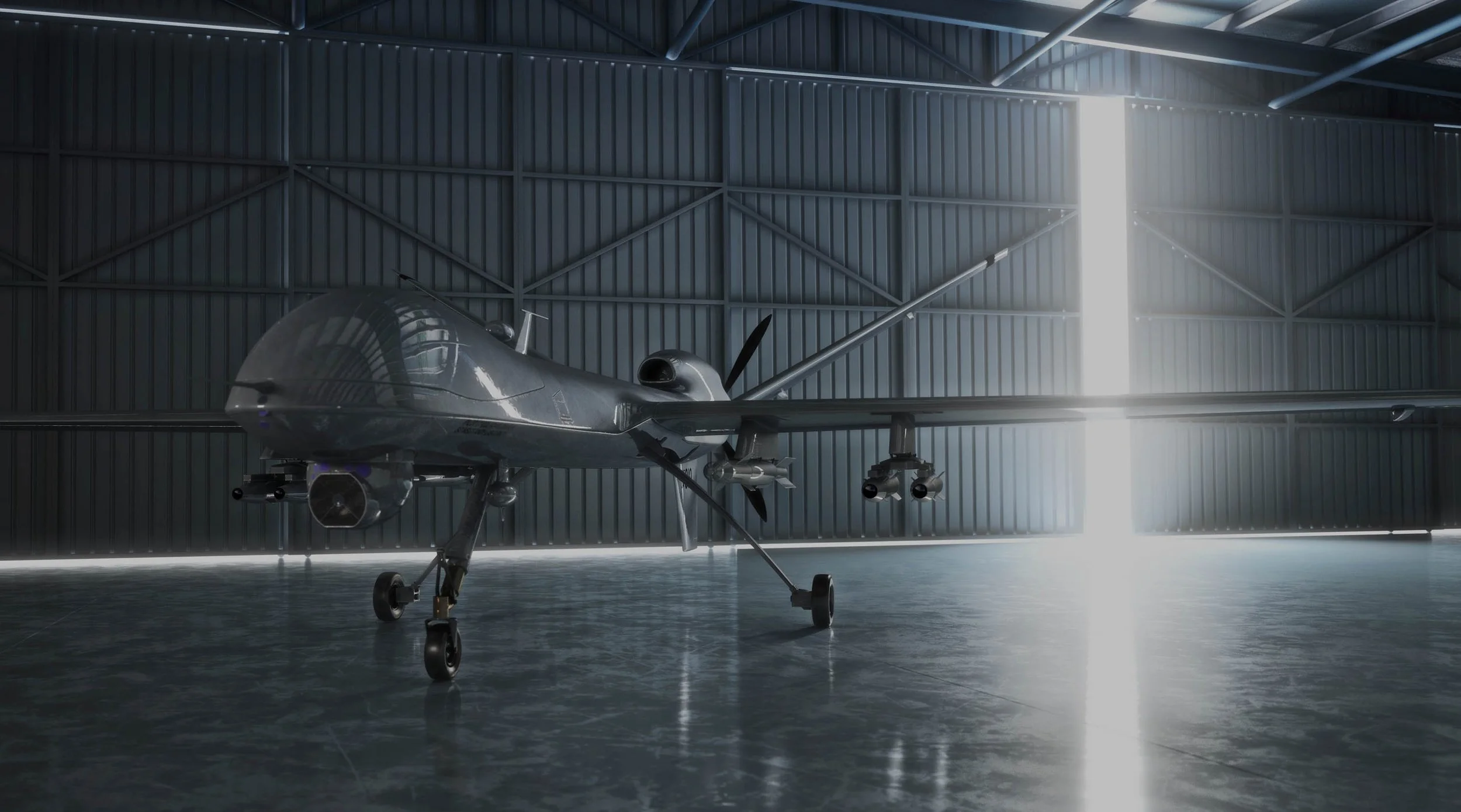 A sleek, gray military drone inside a spacious hangar with metal walls and high ceiling, sunlight streaming through an opening.