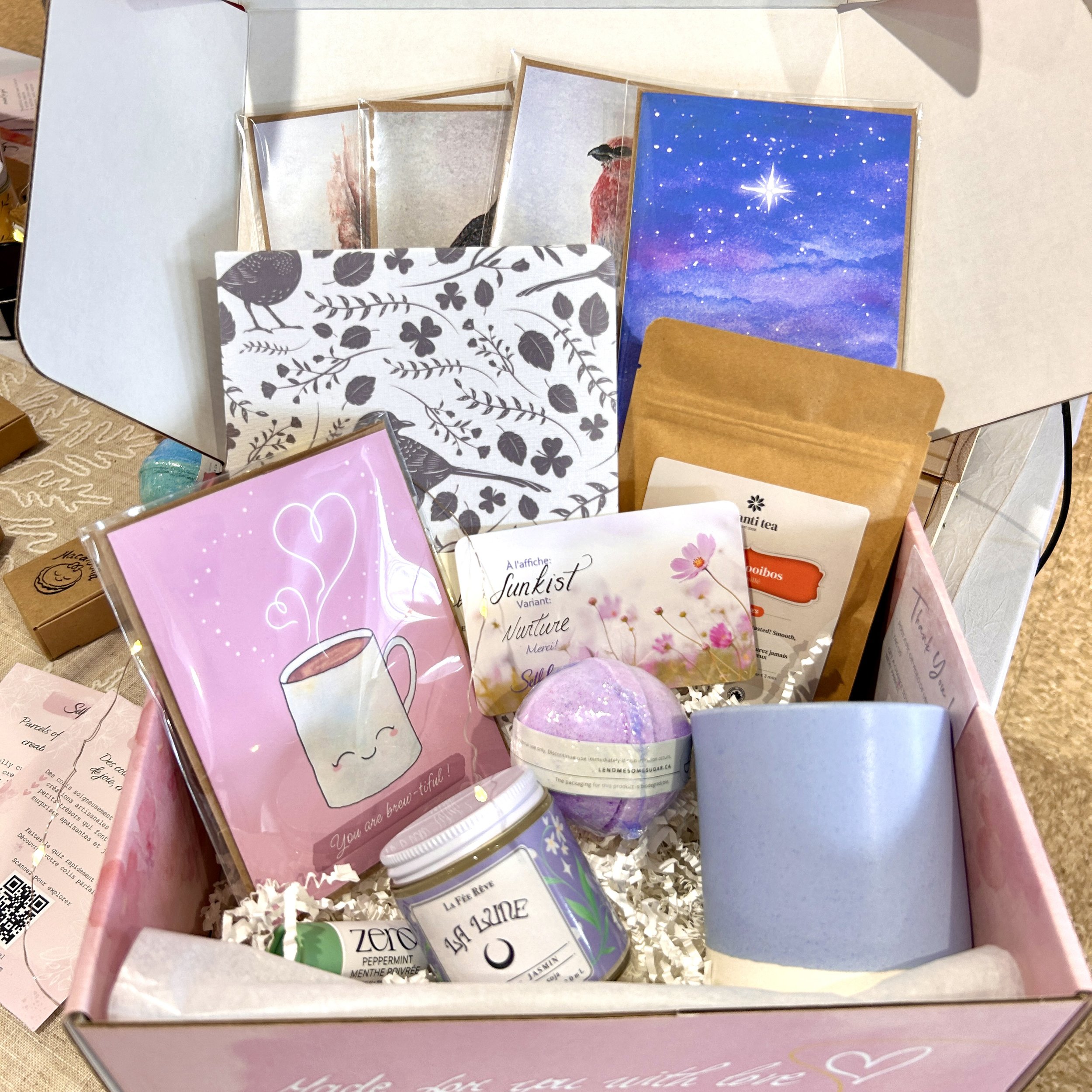 A gift box containing various tea products and related items, including tea sachets, a pink card with a bunny illustration, and other packaged teas with decorative designs.