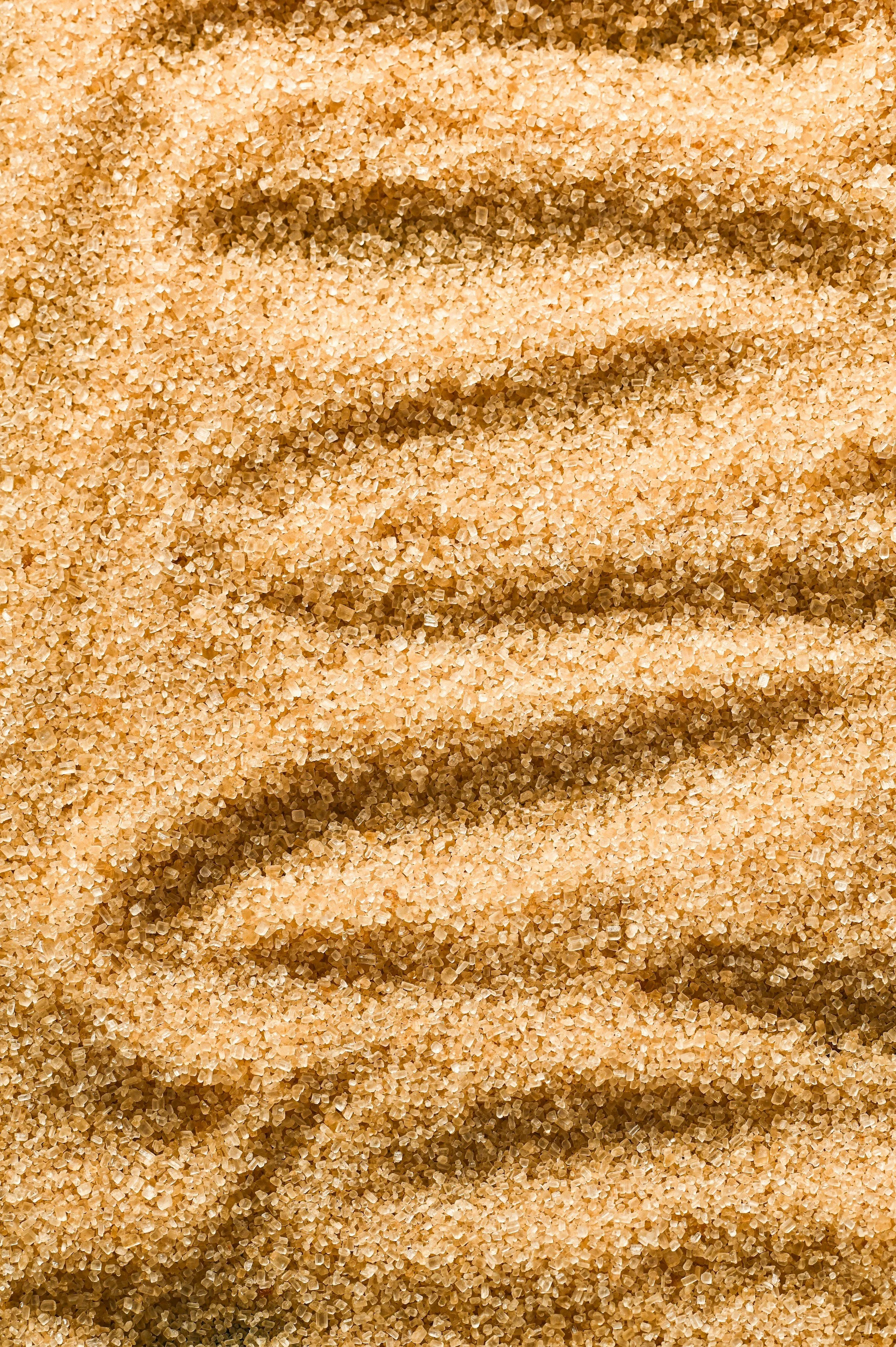 Close-up of light brown sugar crystals, showing granular texture.