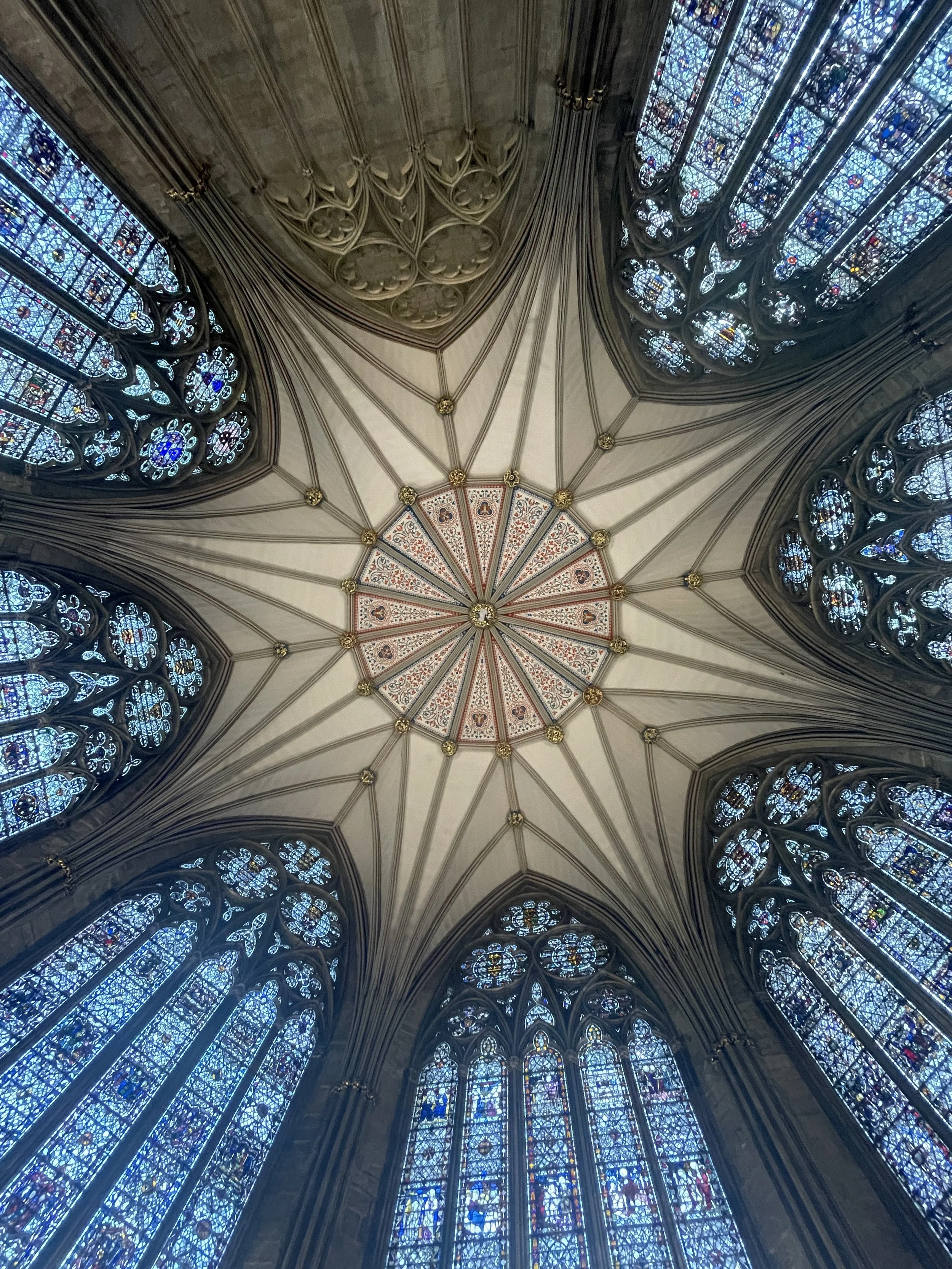 A view of the ceiling inside a cathedral with intricate stained glass windows and gothic architectural elements.