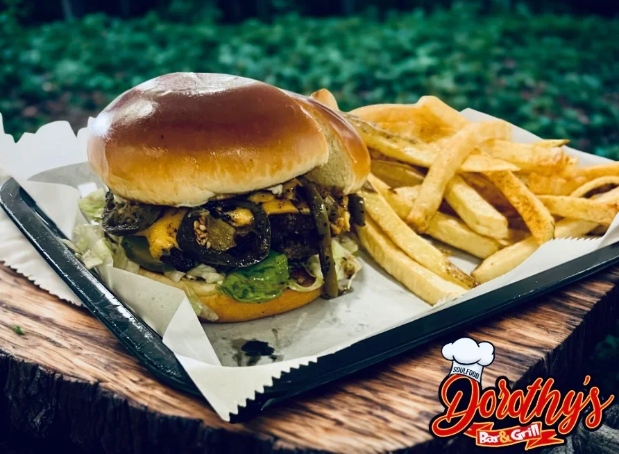 Cheeseburger with jalapeños, lettuce, and pickles served with French fries on a tray at Dorthy's Bar & Grill.