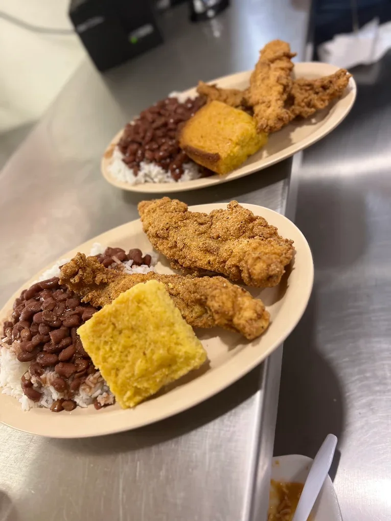 Two plates of Southern comfort food featuring fried chicken, baked cornbread, white rice, and cooked pinto beans.