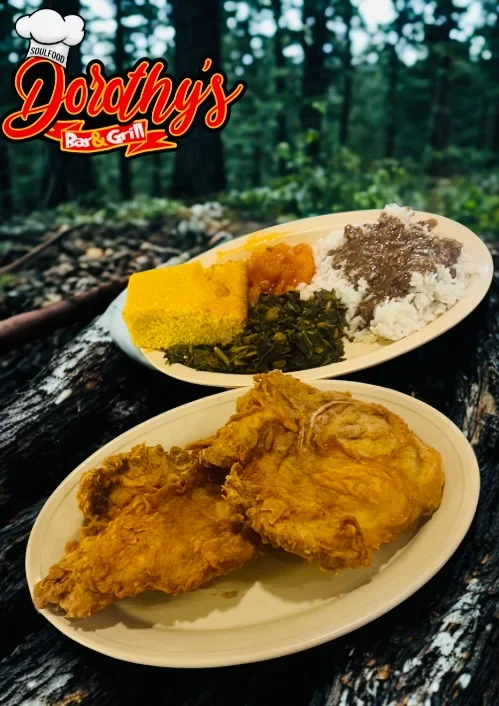 Fried chicken served on a white plate with a side of cooked vegetables and rice, with the logo of Dorothy's Bar & Grill in the top left corner, set against a forest background.